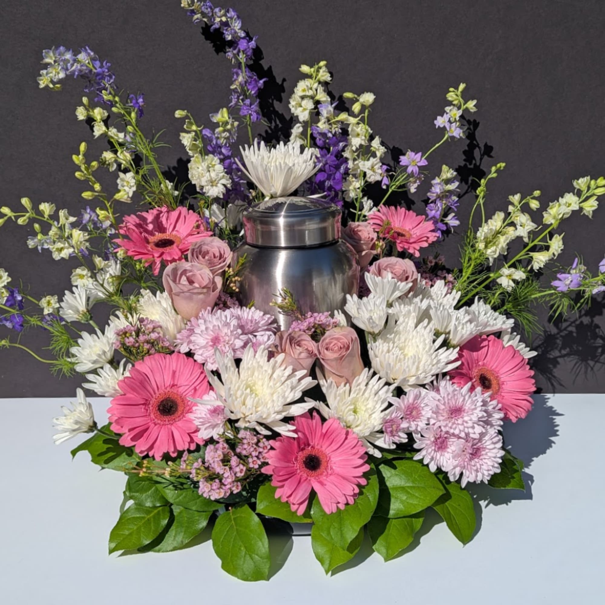 Pink and white flowers arranged around a stainless steel urn