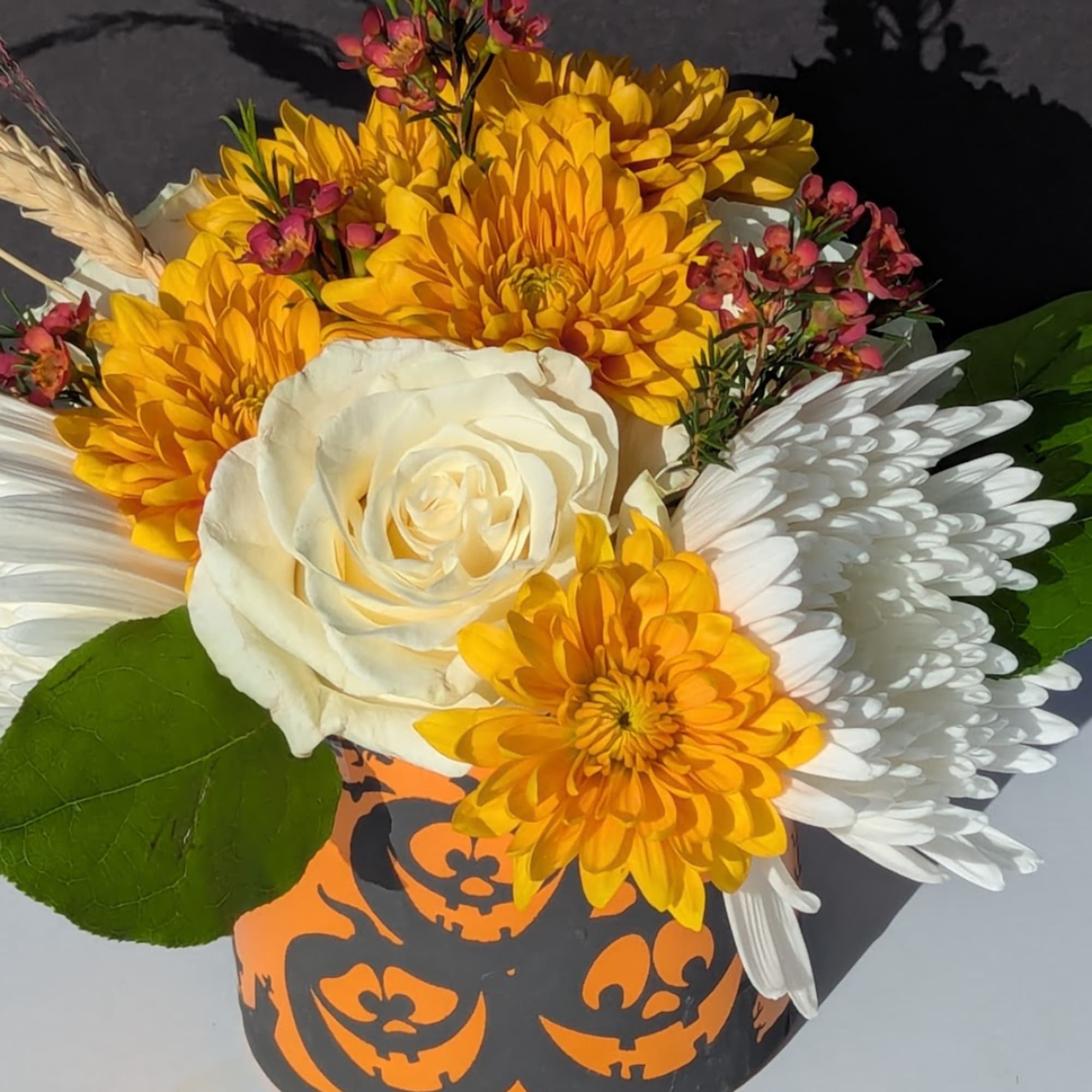 Bouquet of yellow and white flowers in a Halloween pumpkin container