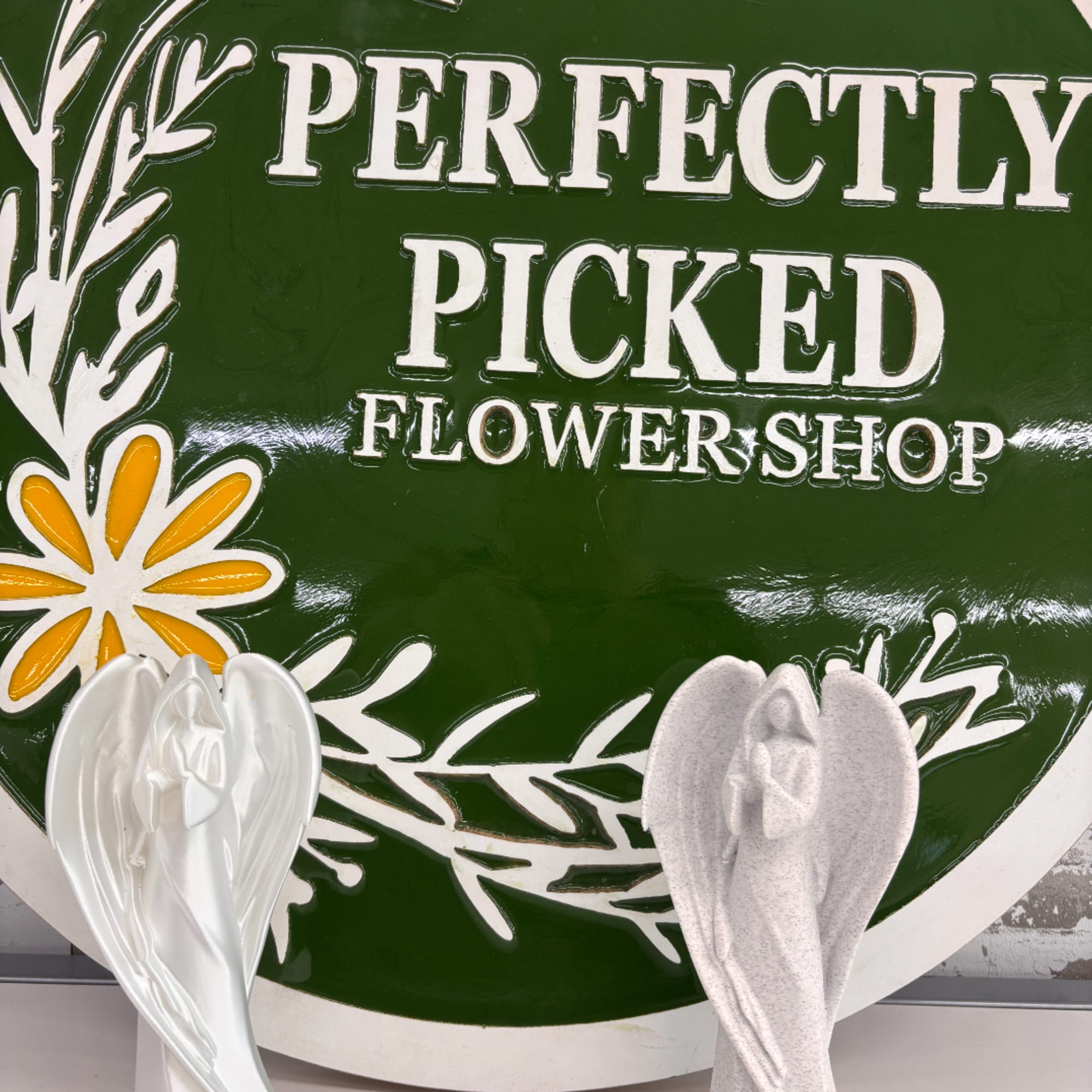 Green flower shop sign with white lettering and floral graphics