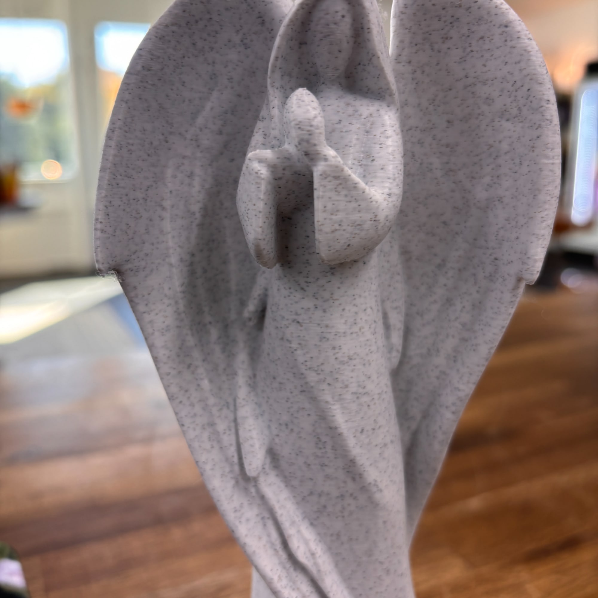 Gray angel figurine with folded wings and hands in prayer