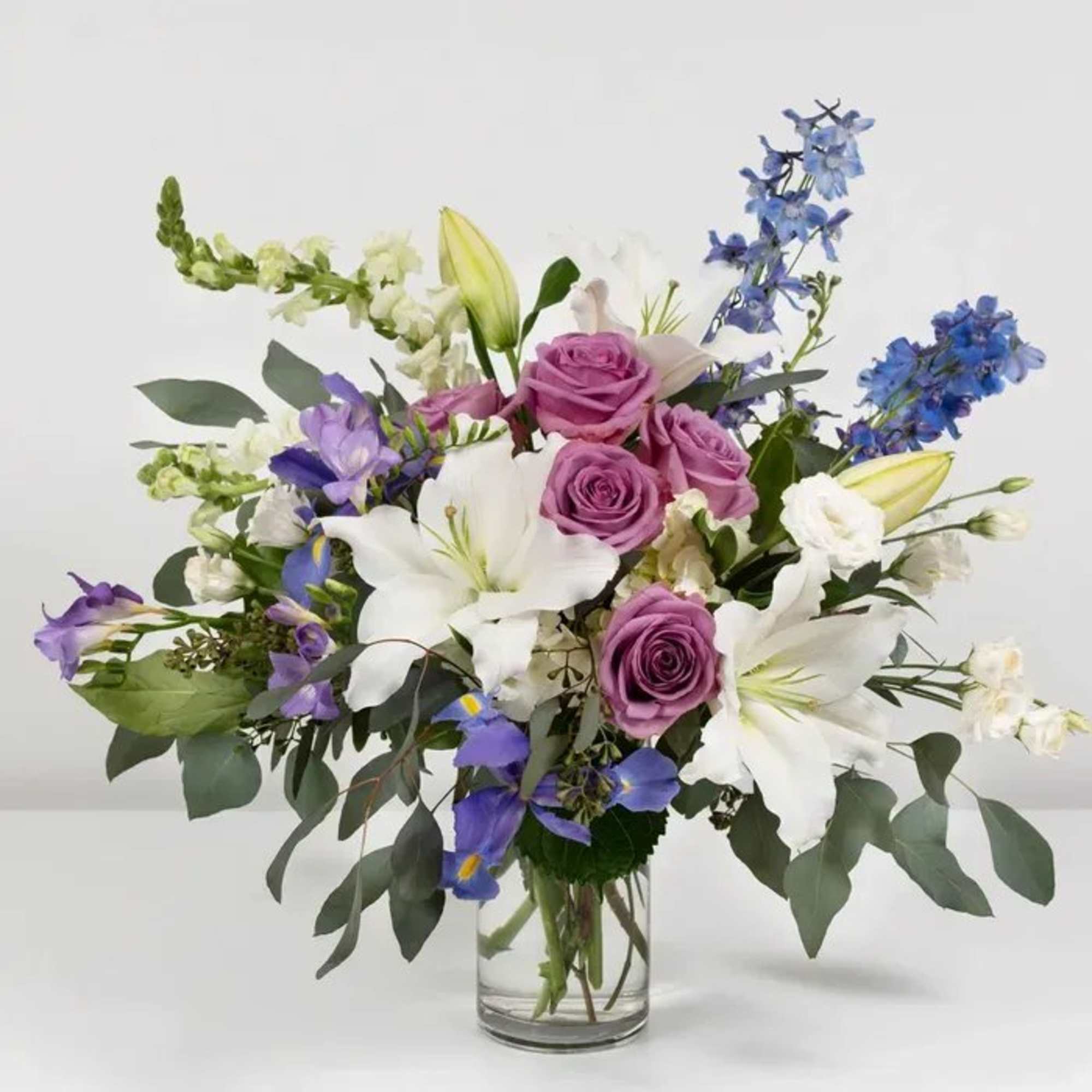 Bouquet of purple roses and white lilies in a clear glass vase