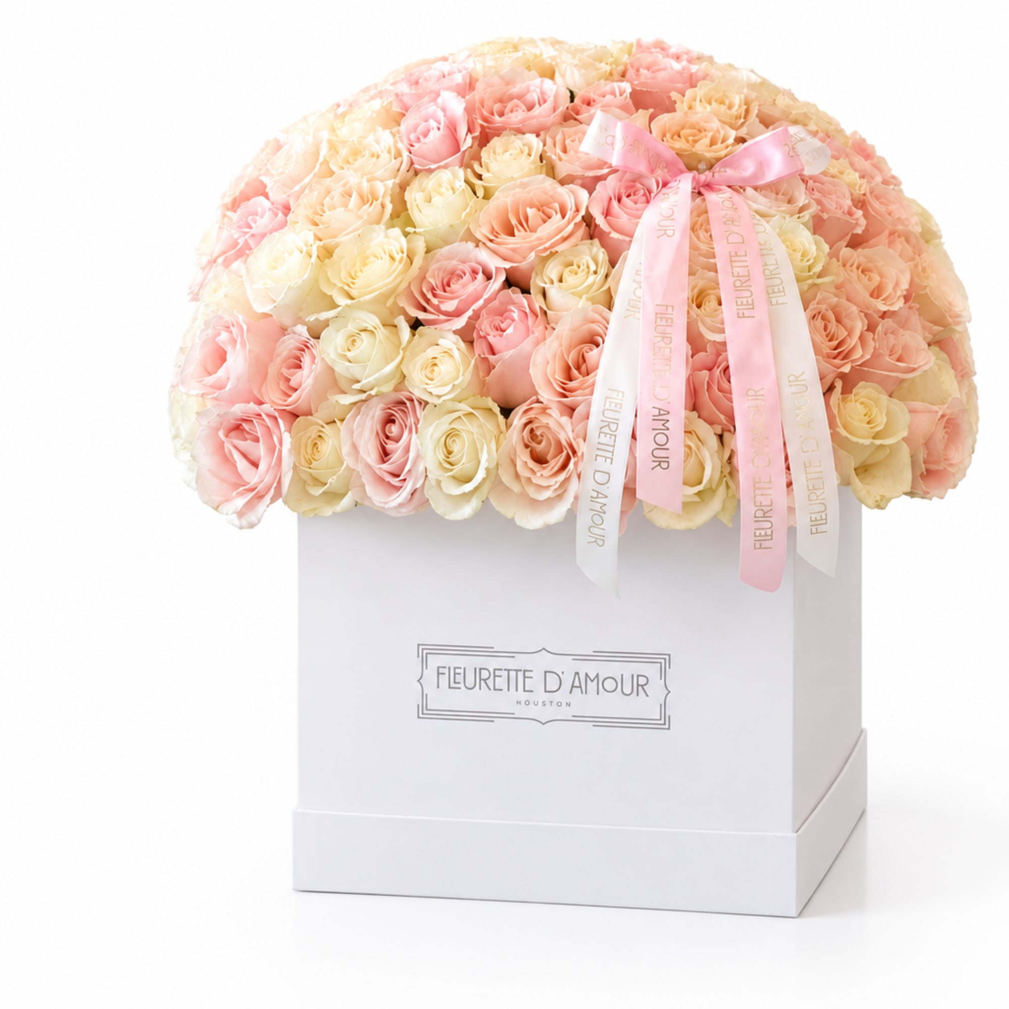 Pastel roses arranged in a white gift box with pink ribbons