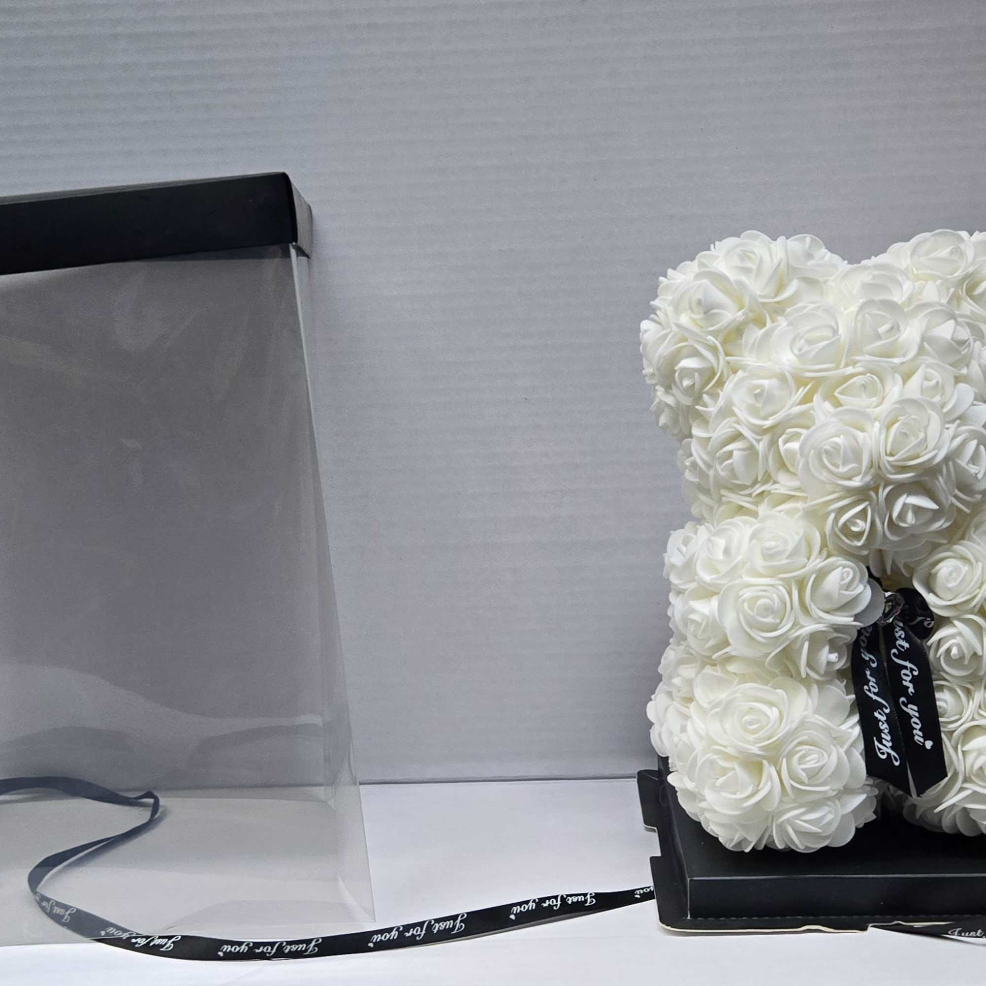 White rose teddy bear in a clear gift box with black ribbon