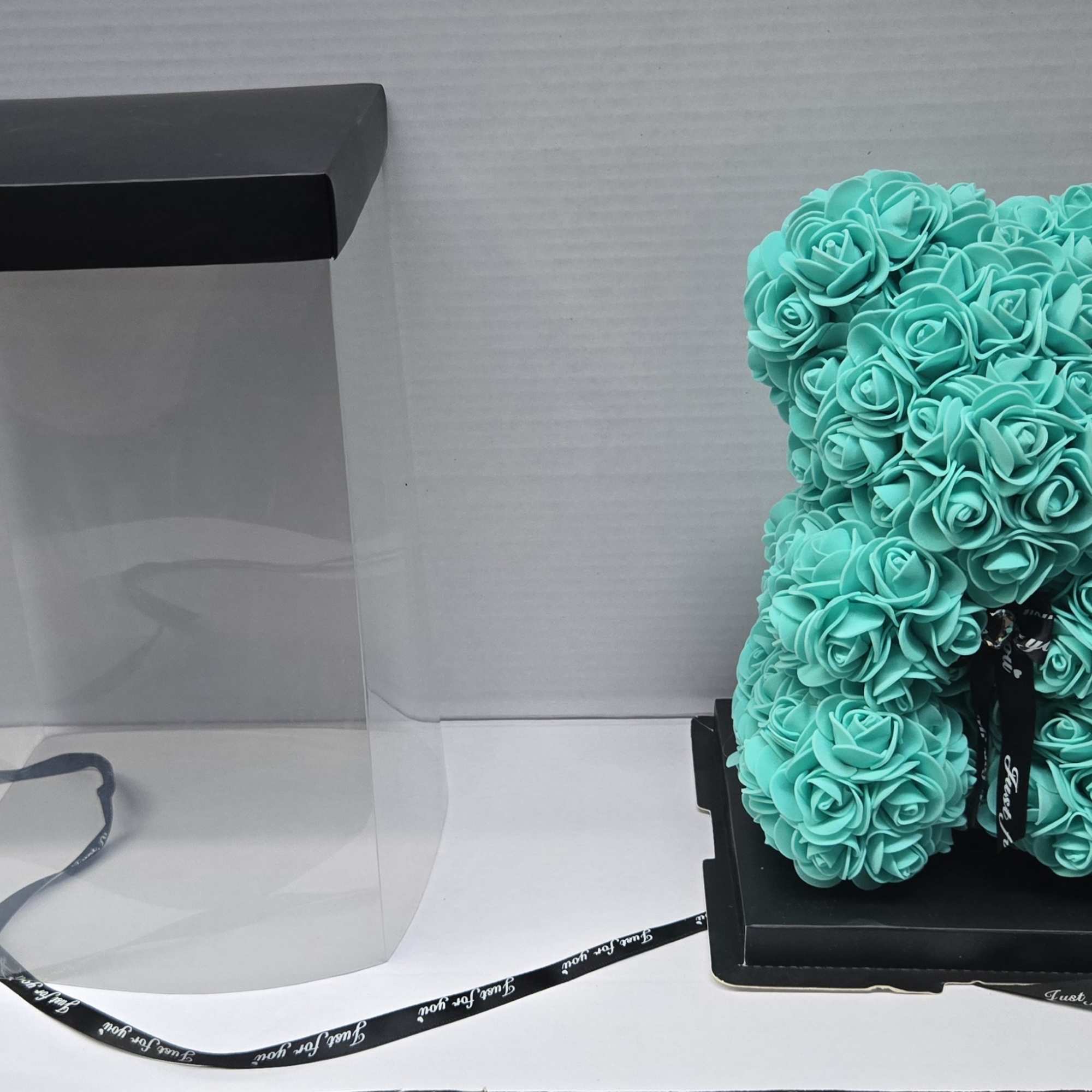 Turquoise rose-shaped teddy bear in a clear gift box with black lid