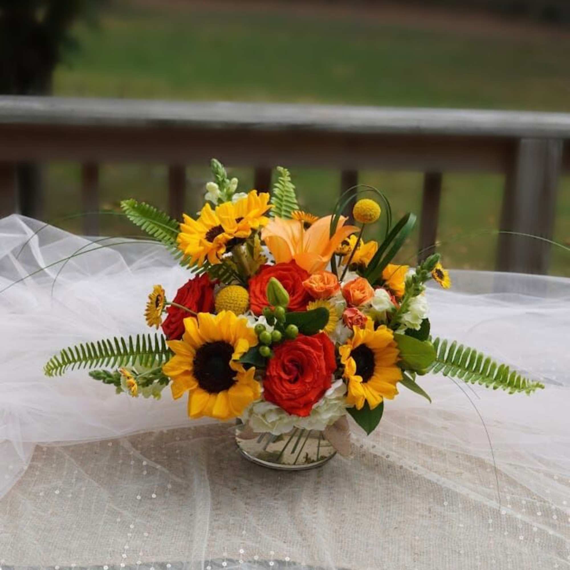 Bright bouquet of sunflowers and red roses in a glass vase