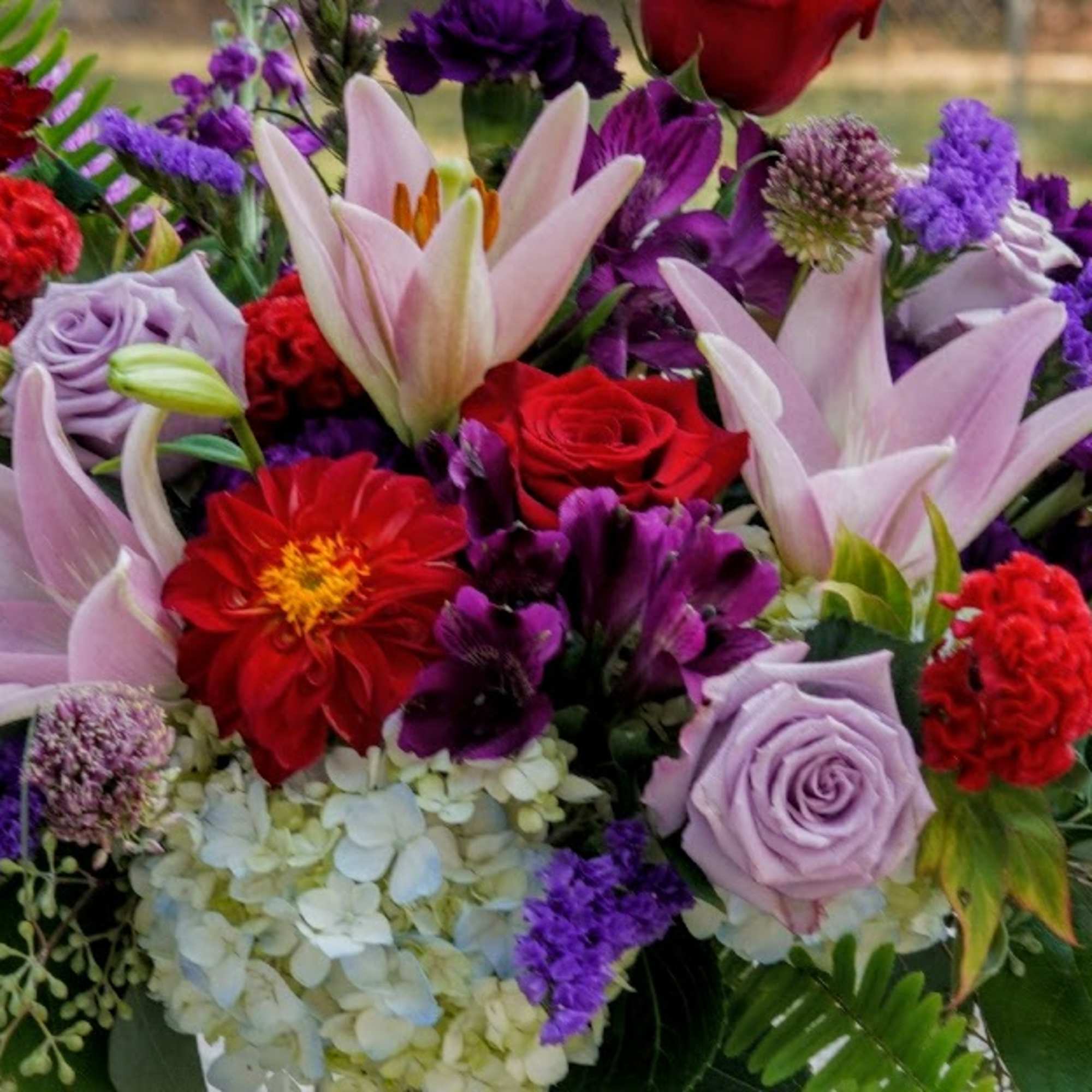Mixed bouquet with pink lilies, red and lavender roses, and purple flowers