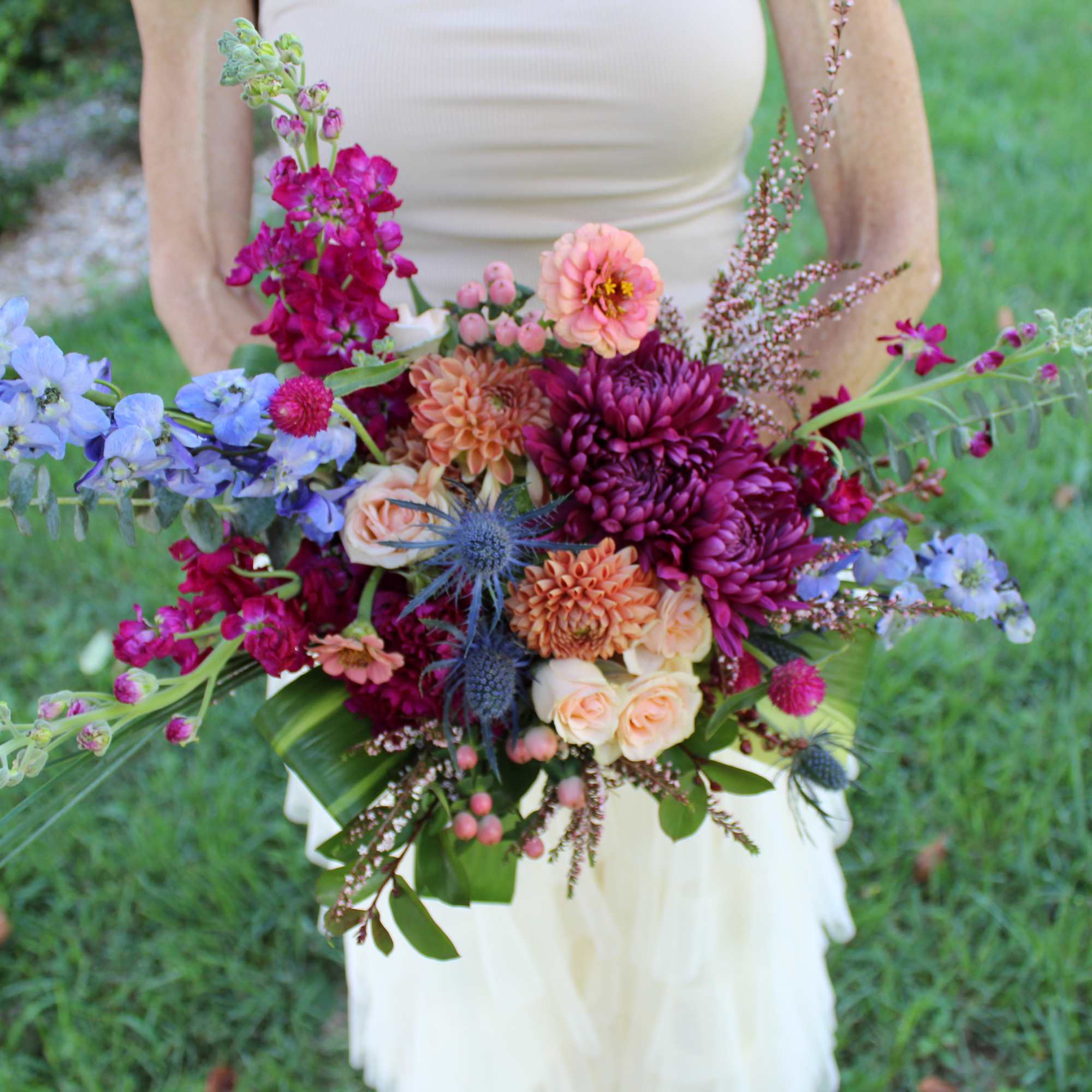 Bride holding a colorful bouquet with blue and magenta flowers
