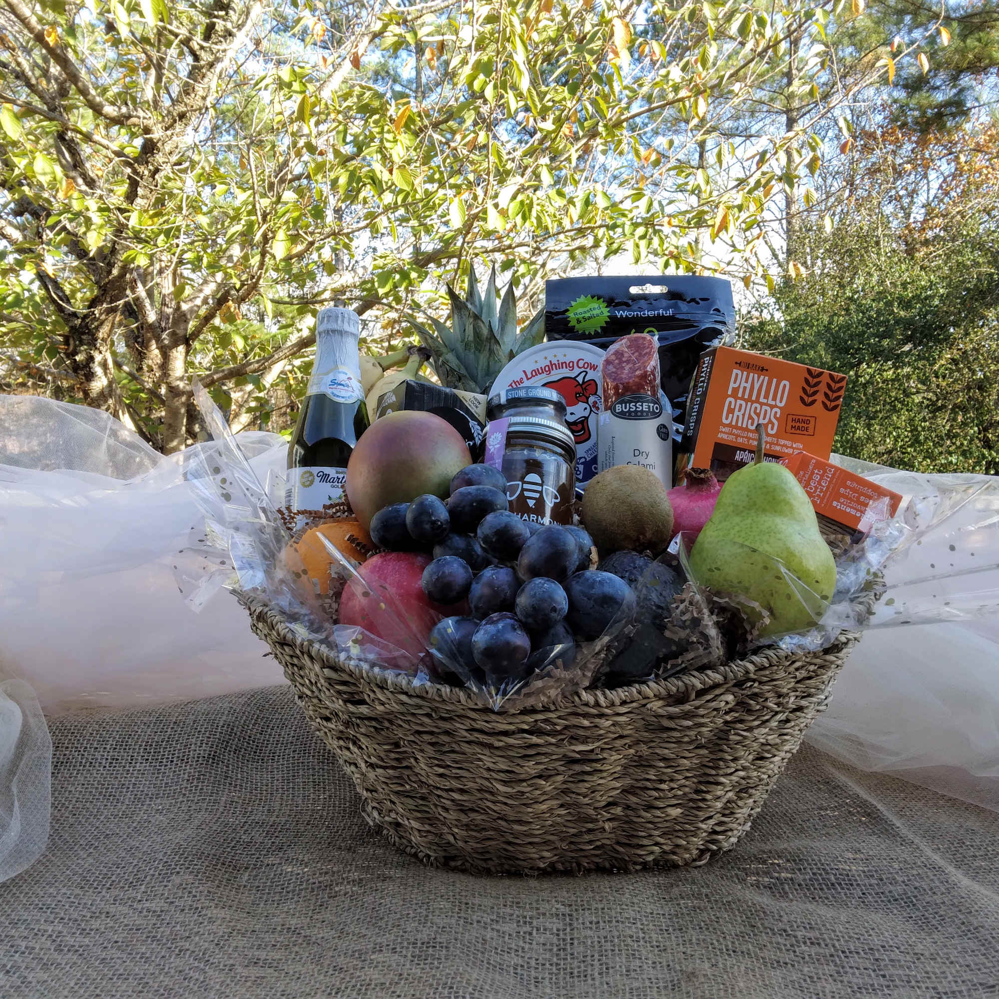 Fruit and snack gift basket in a woven basket with tulle wrap