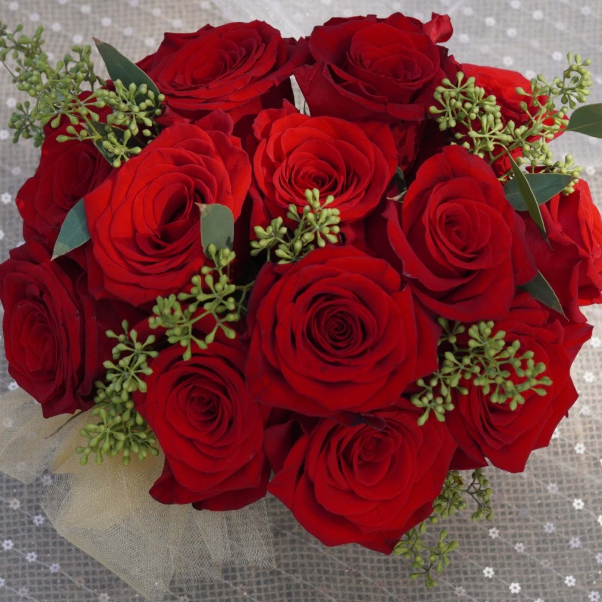 Bouquet of red roses with small green filler and a sheer ribbon