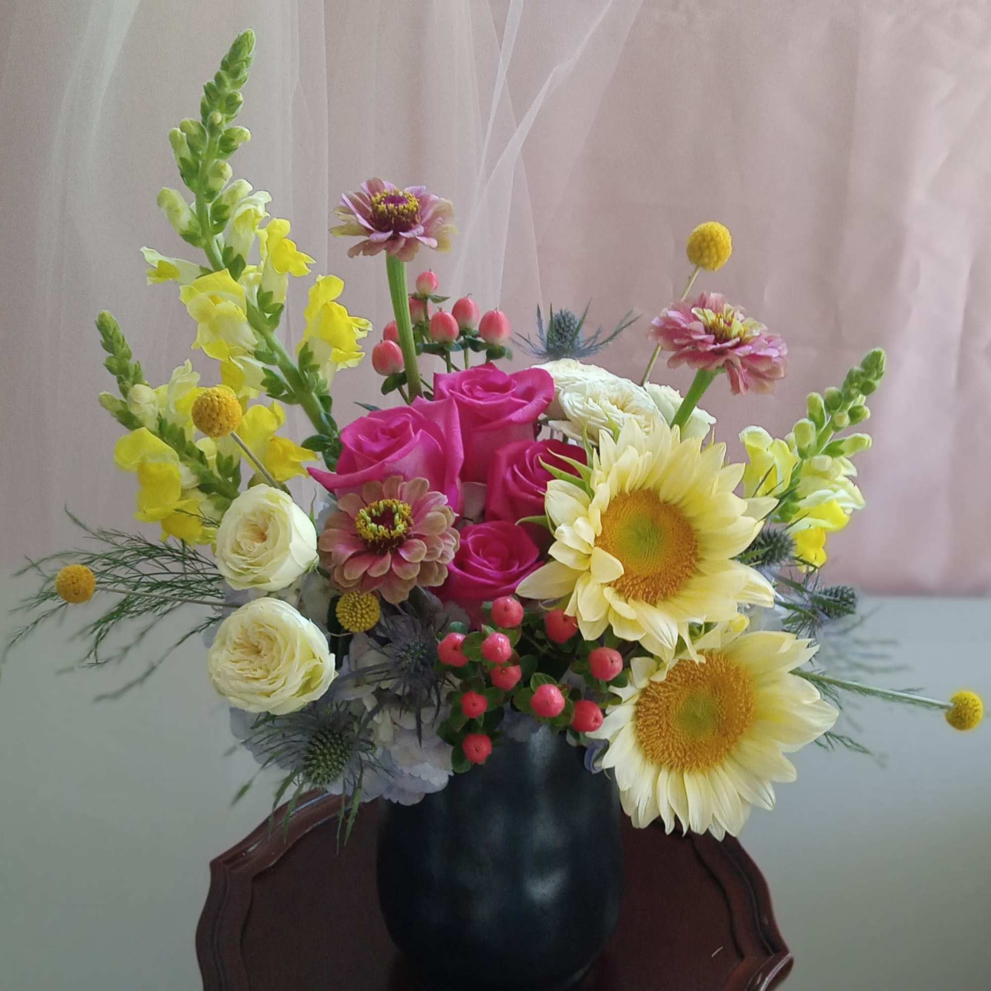 Mixed bouquet in a black vase with pink roses and yellow sunflowers