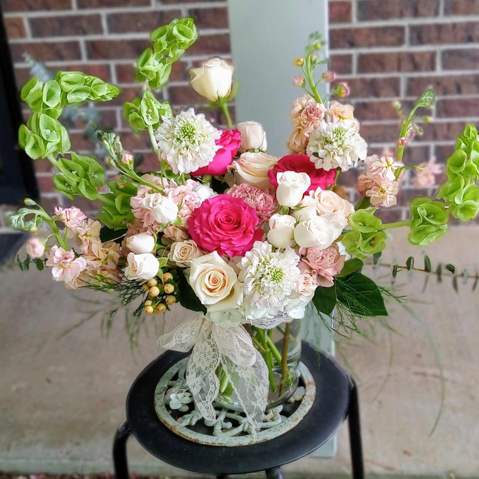 Mixed bouquet of pink and white roses with green bells of Ireland in a glass vase