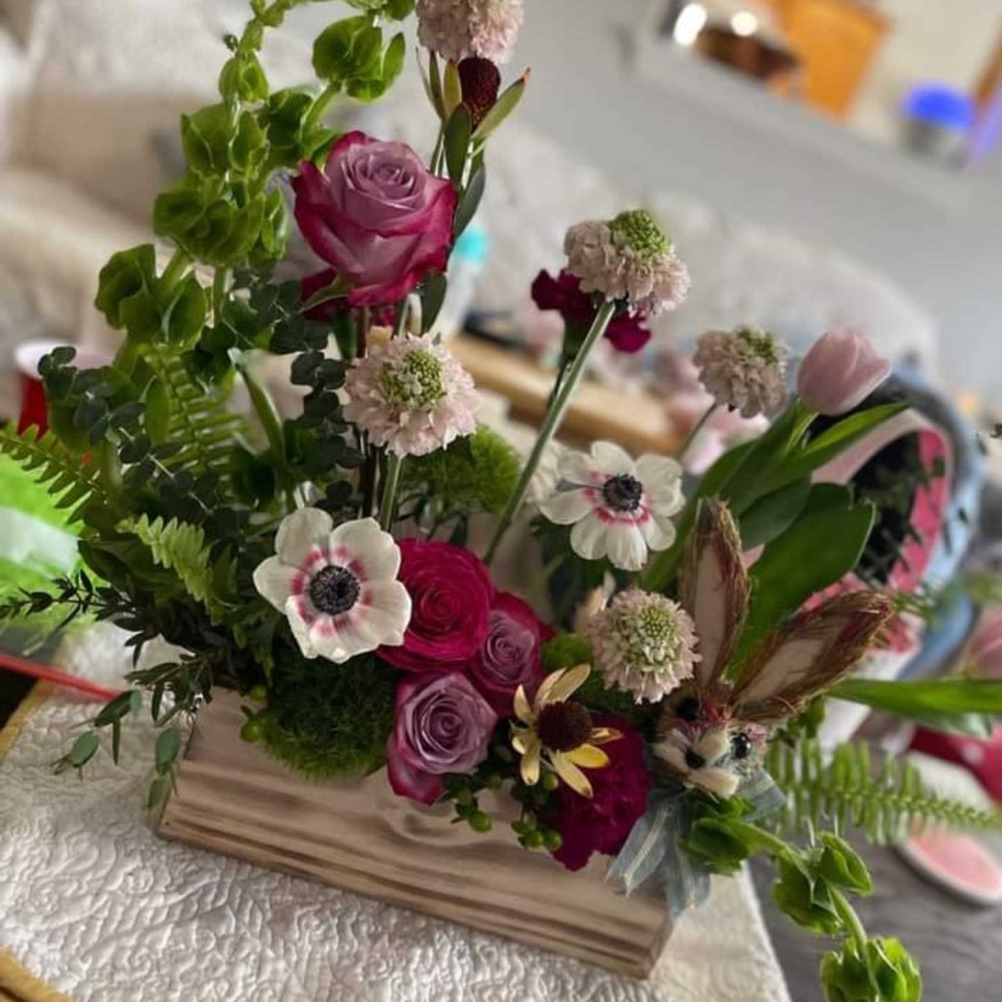 Mixed bouquet with pink roses and white anemones in a wooden base