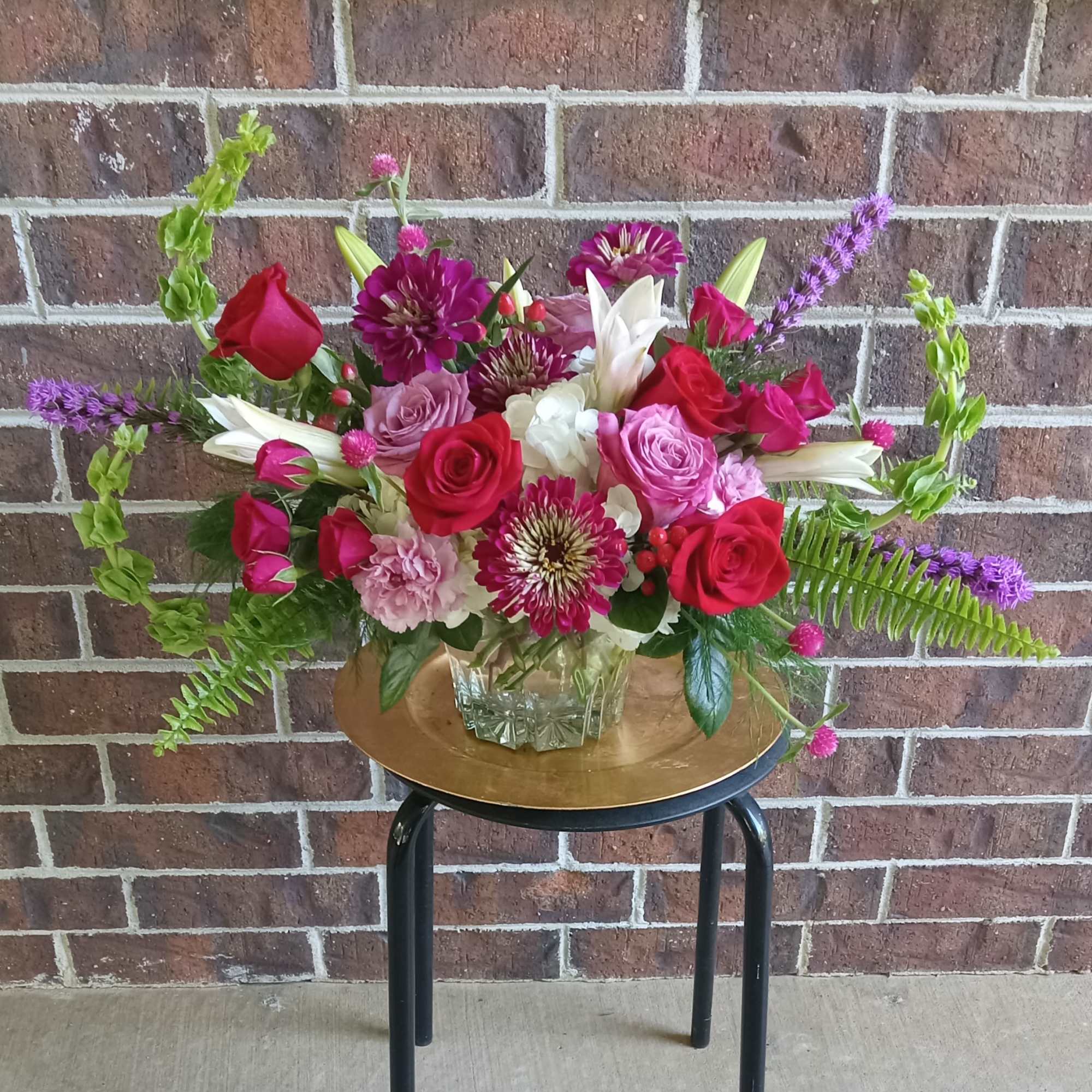 Mixed bouquet of red and pink roses with white lilies in a glass vase