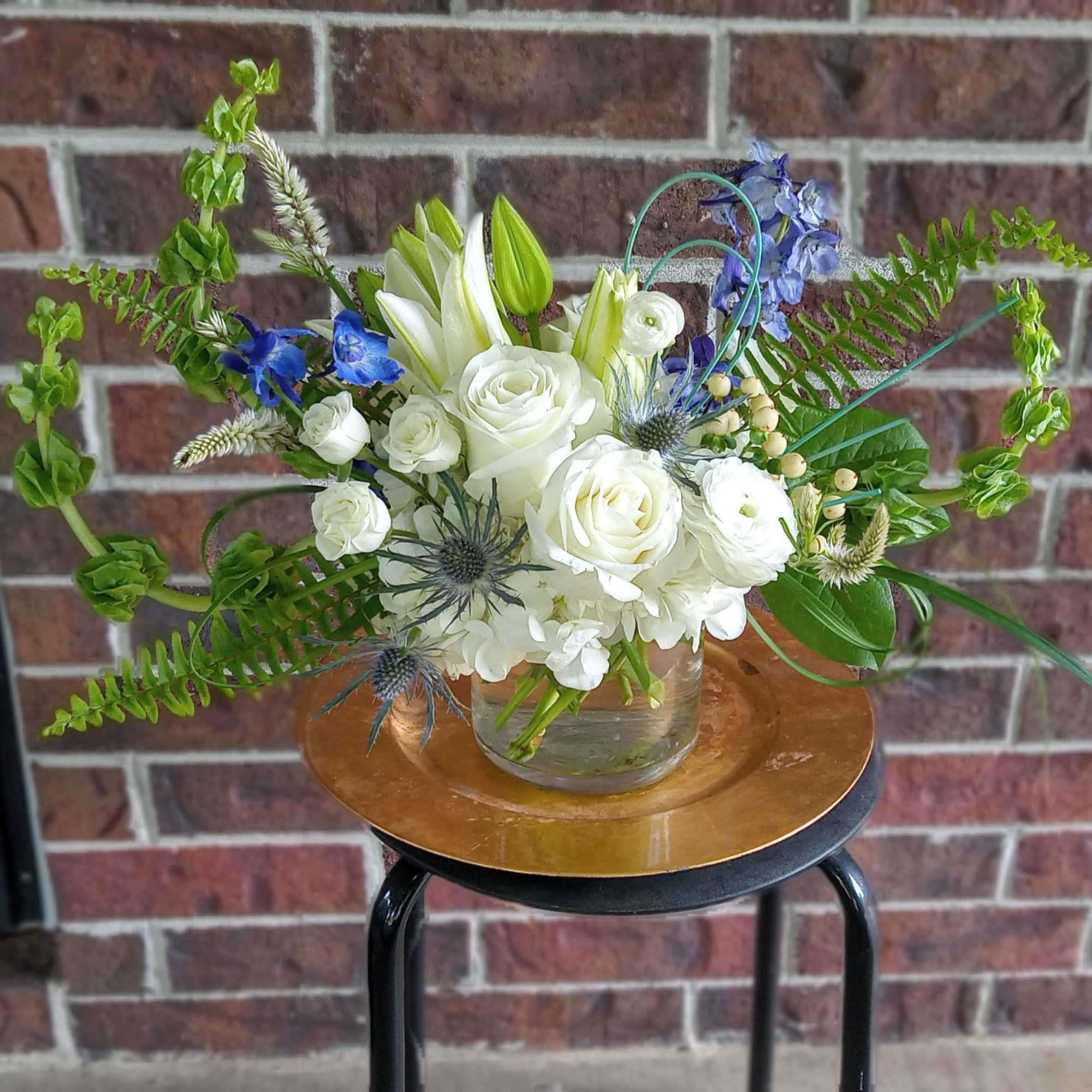 White rose bouquet in a glass vase with blue accents