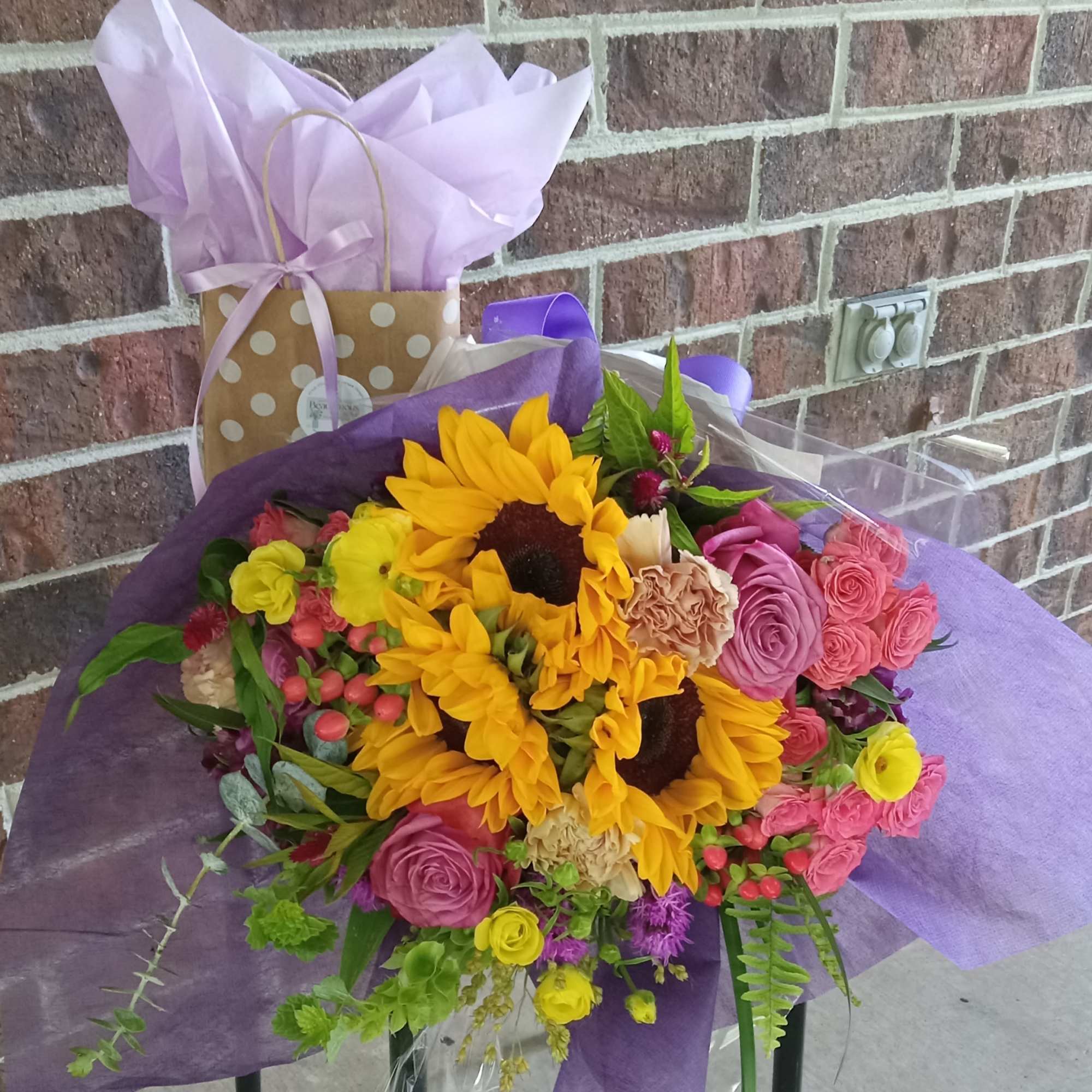 Bouquet of sunflowers and pink roses wrapped in purple paper