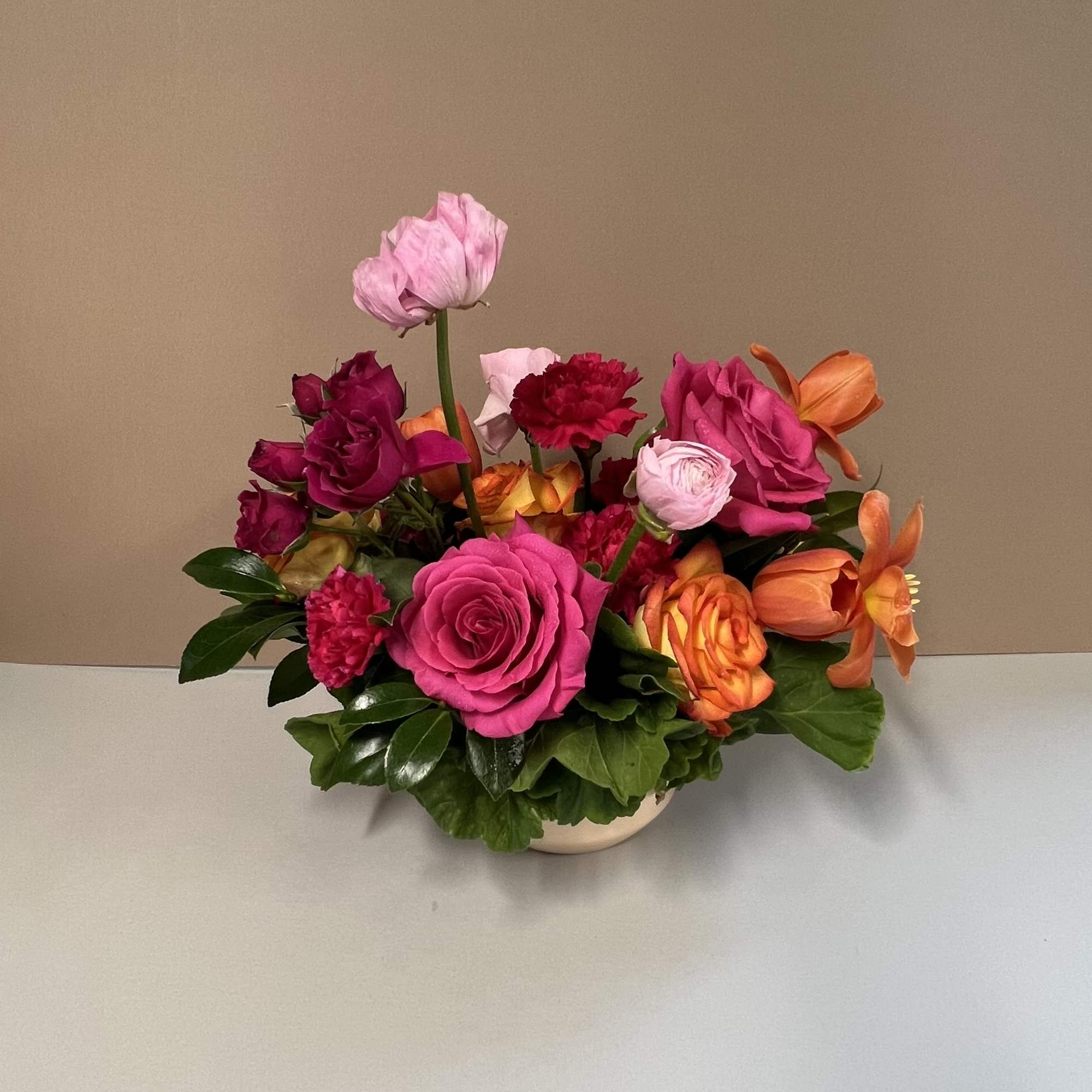 Bright mixed bouquet of pink, orange, and red flowers in a low vase