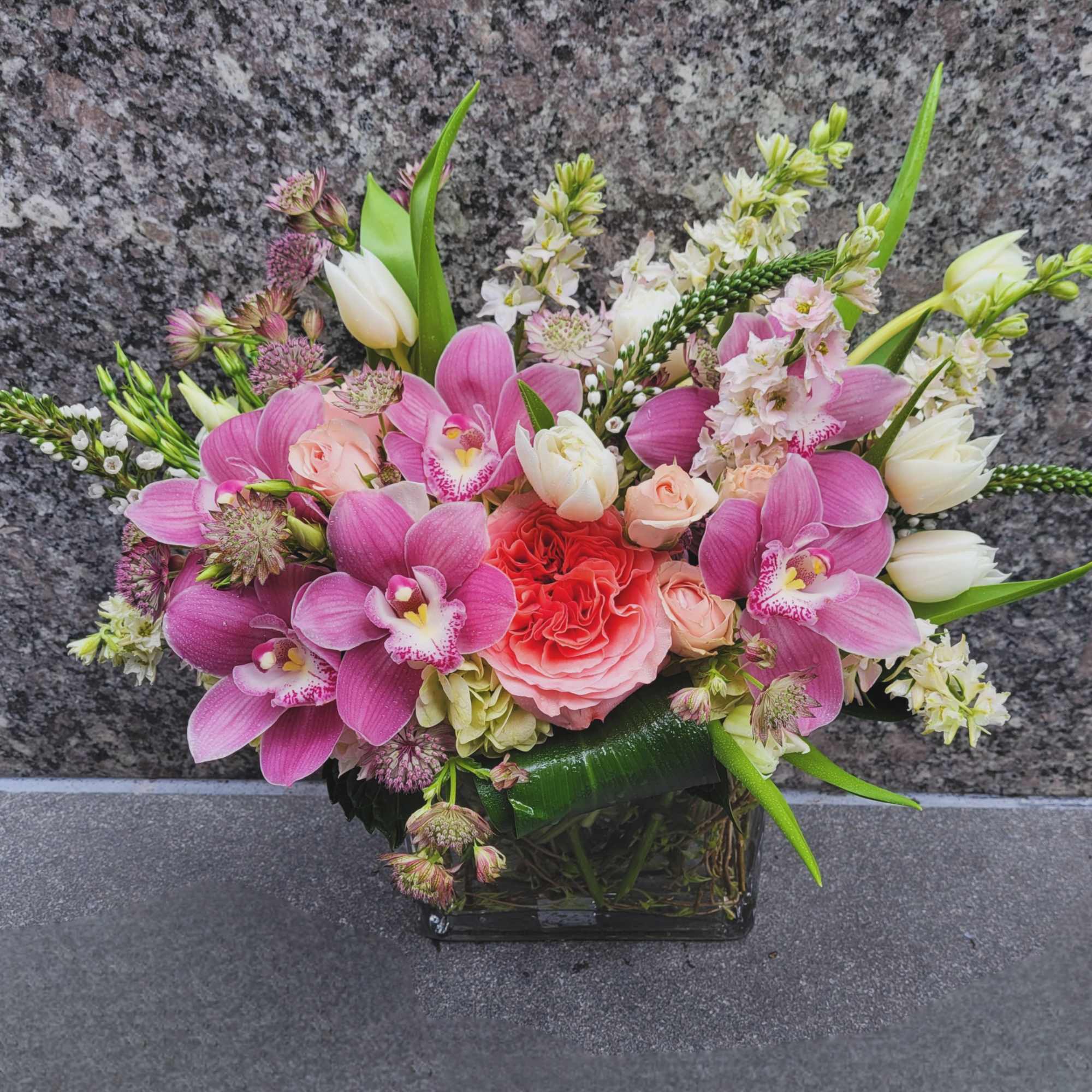 Radiant pink cymbidium orchids, soft garden roses, and pristine white tulips dance