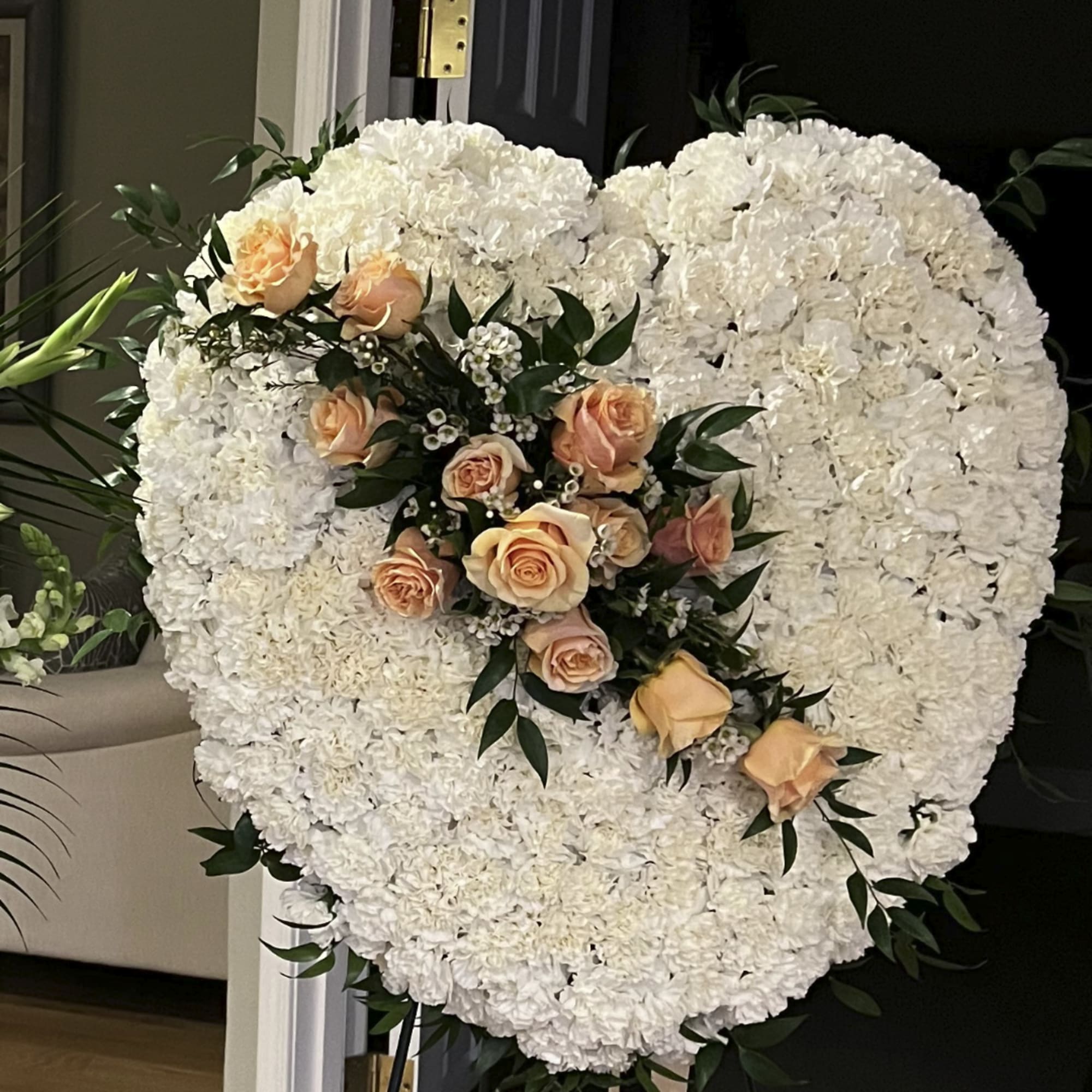 Heart-shaped white floral arrangement with peach roses