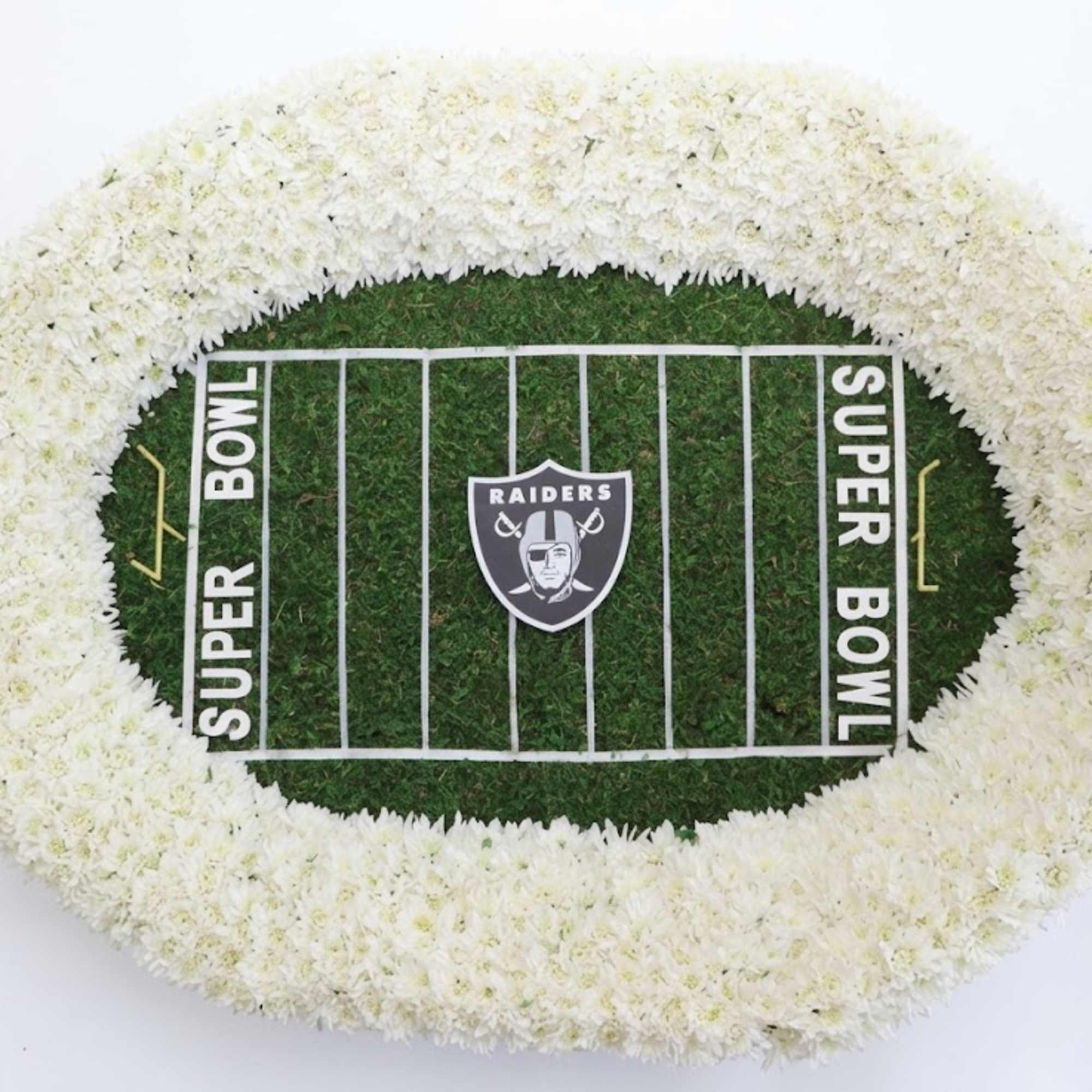 Oval white floral wreath around a football field display with Raiders logo