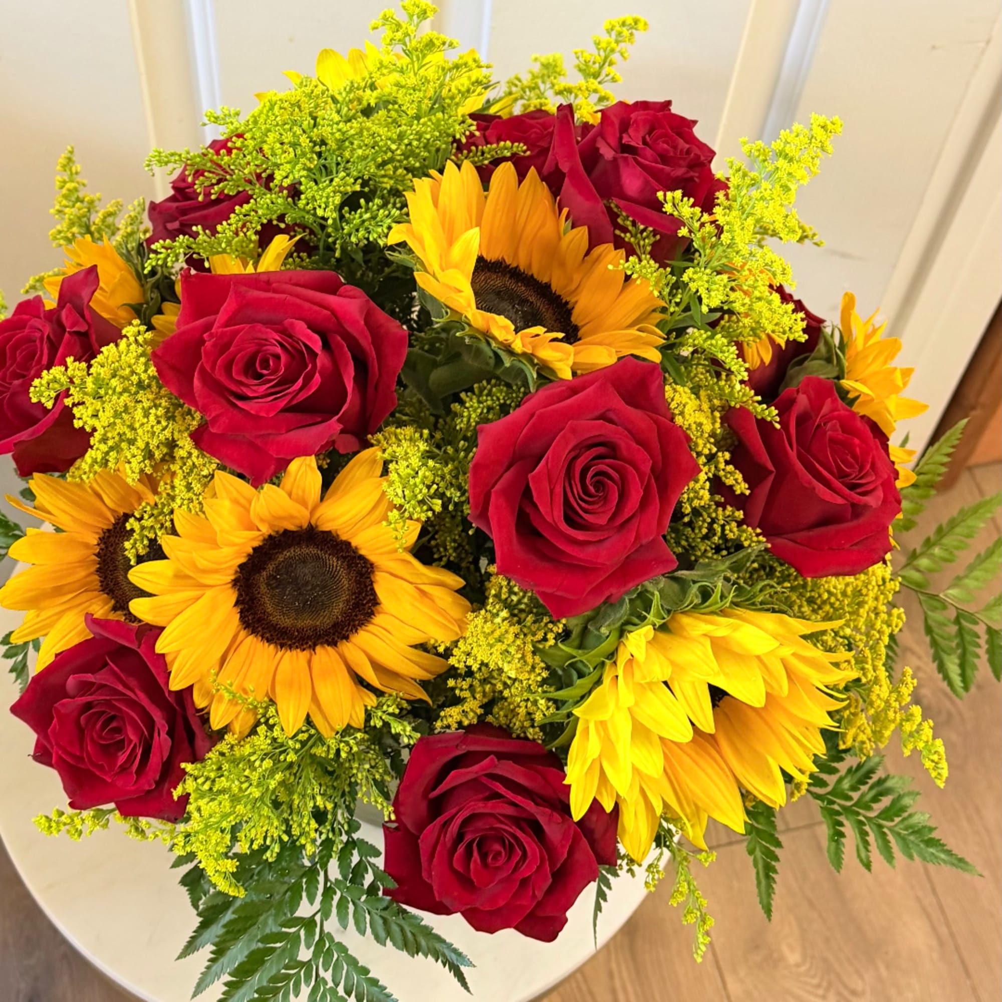Bouquet of red roses and yellow sunflowers with green filler