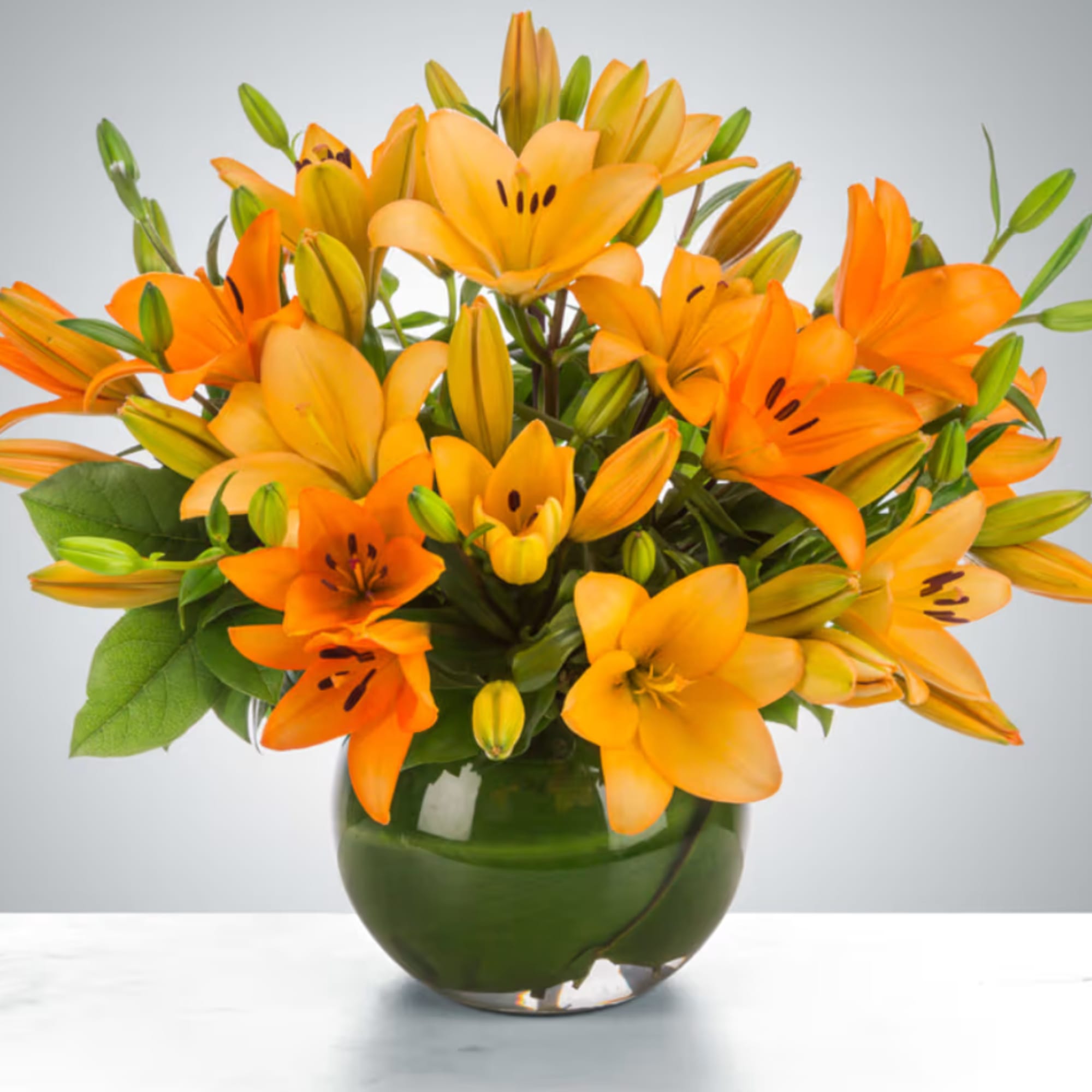 Orange lilies arranged in a green glass vase