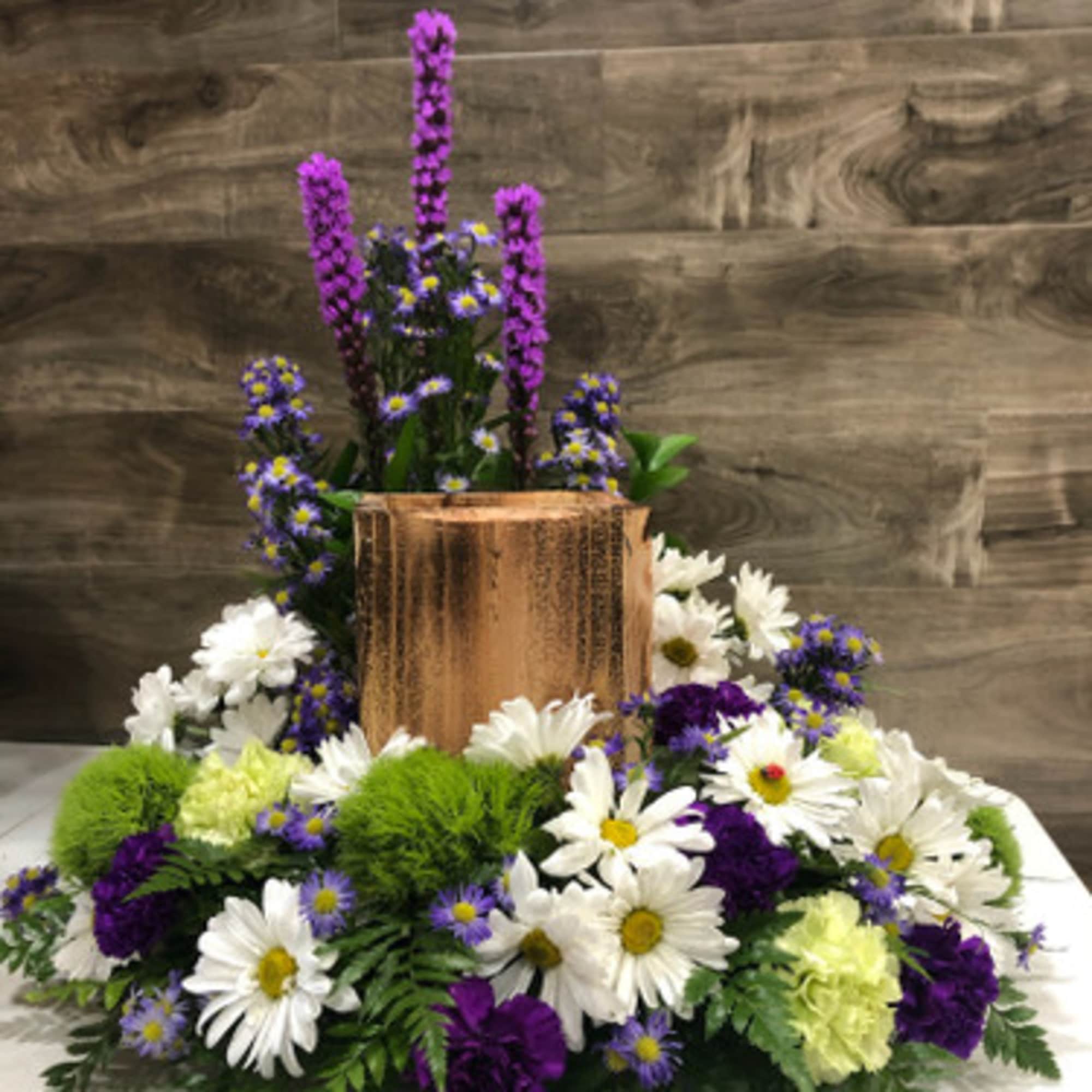 White daisies and purple flowers arranged around a copper vase