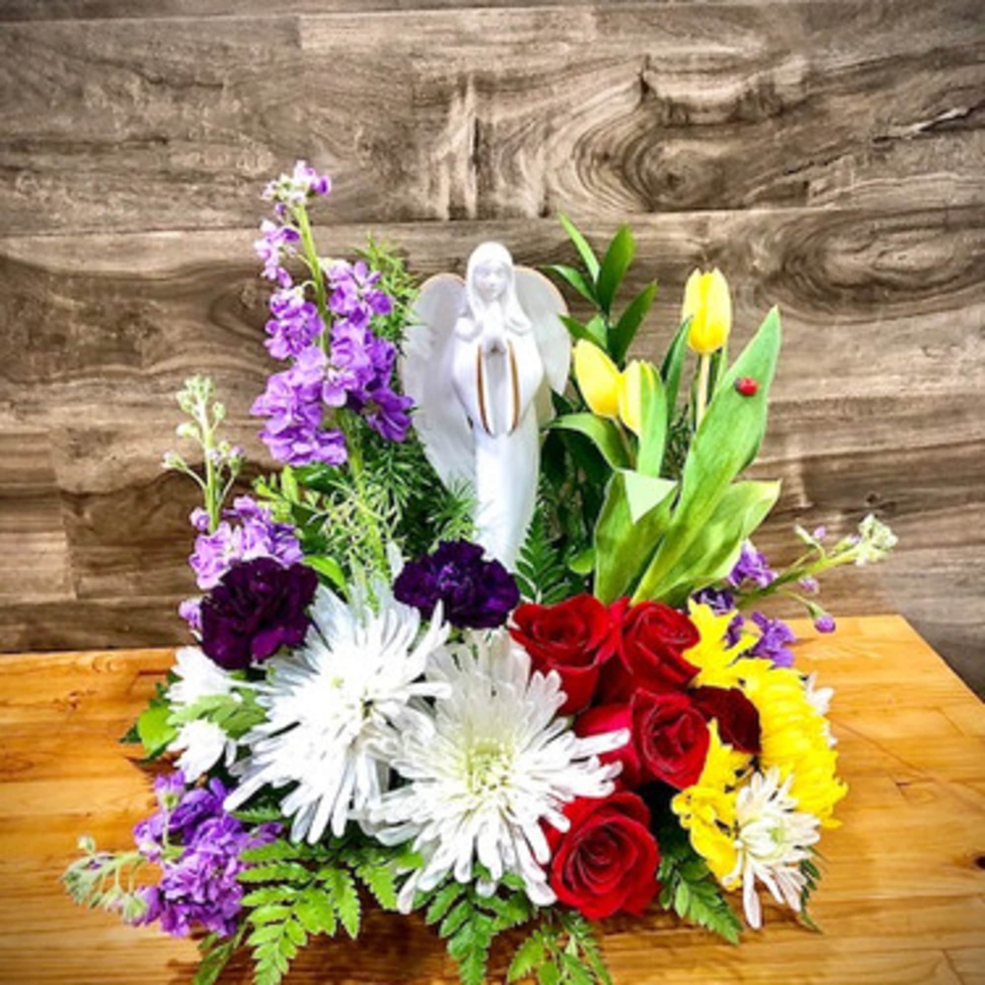 Colorful floral arrangement with an angel figurine in the center