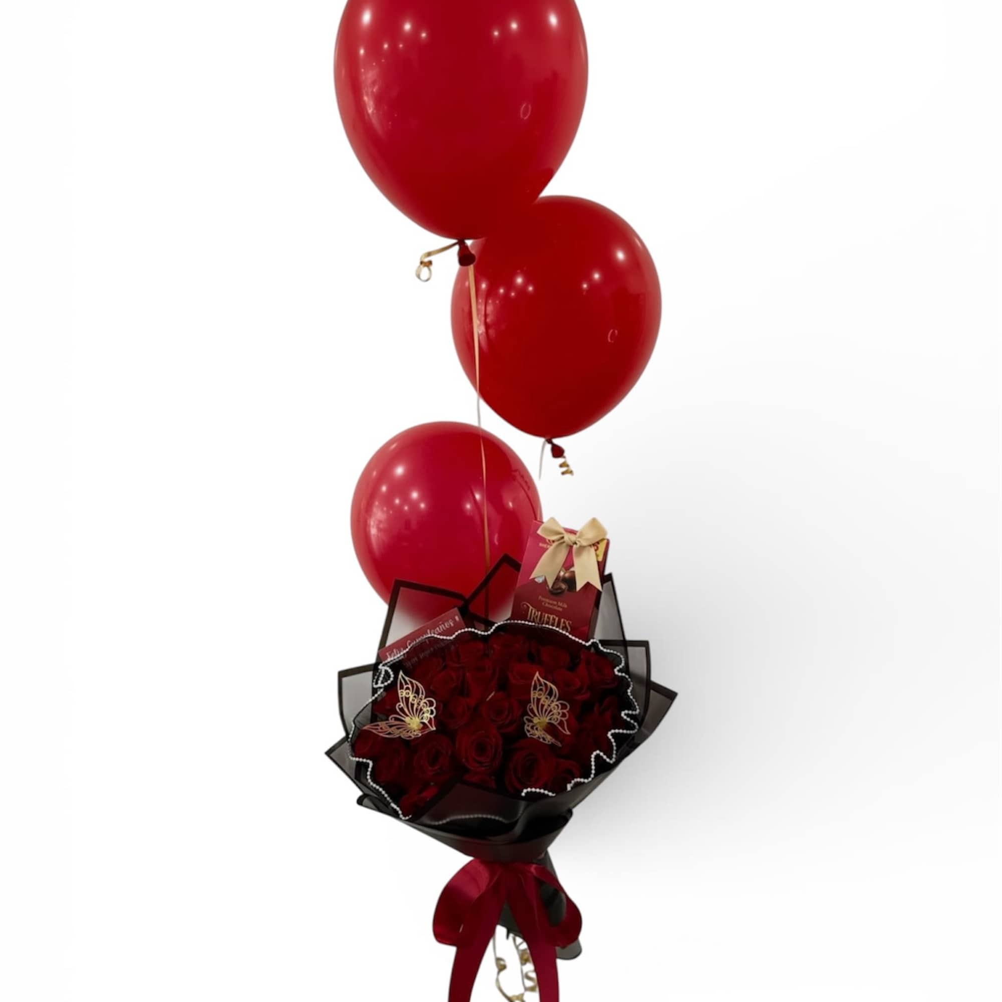 Red rose bouquet with a chocolate box and three red balloons tied above.