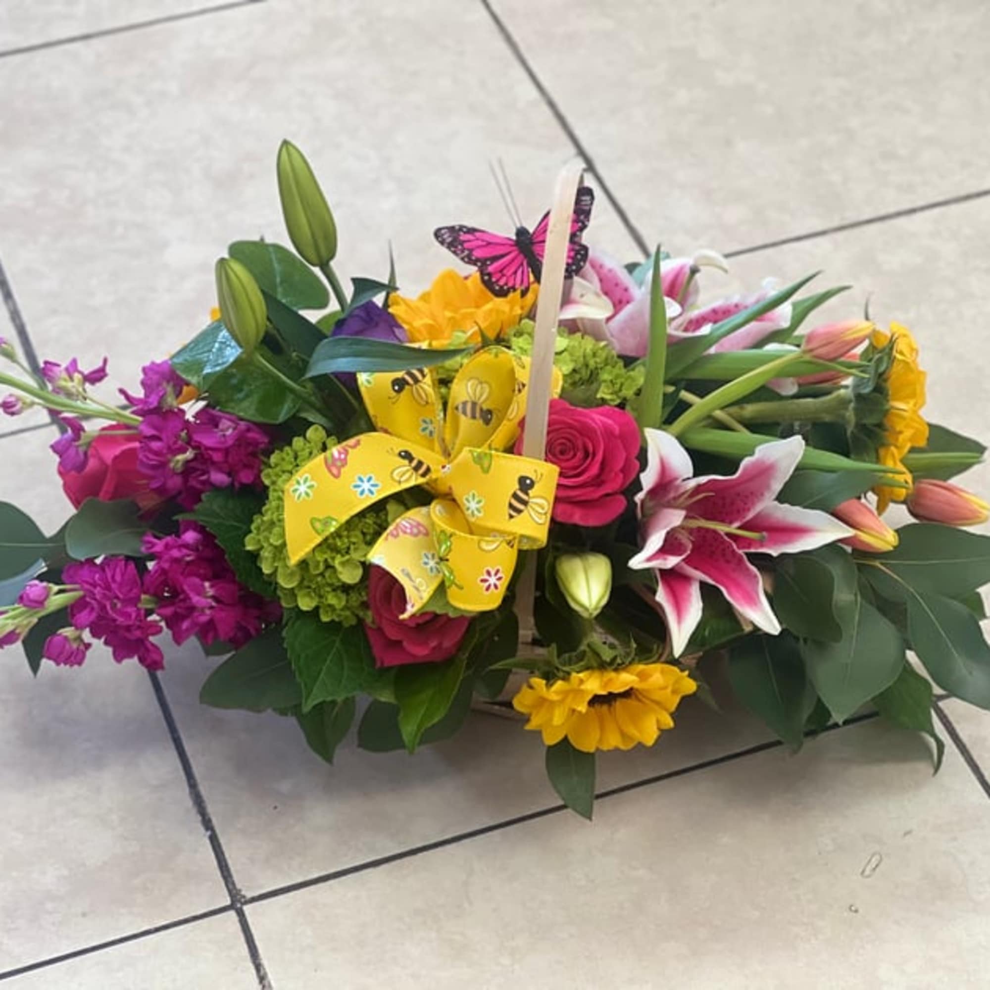 Colorful mixed flower basket with lilies, roses, and a yellow ribbon