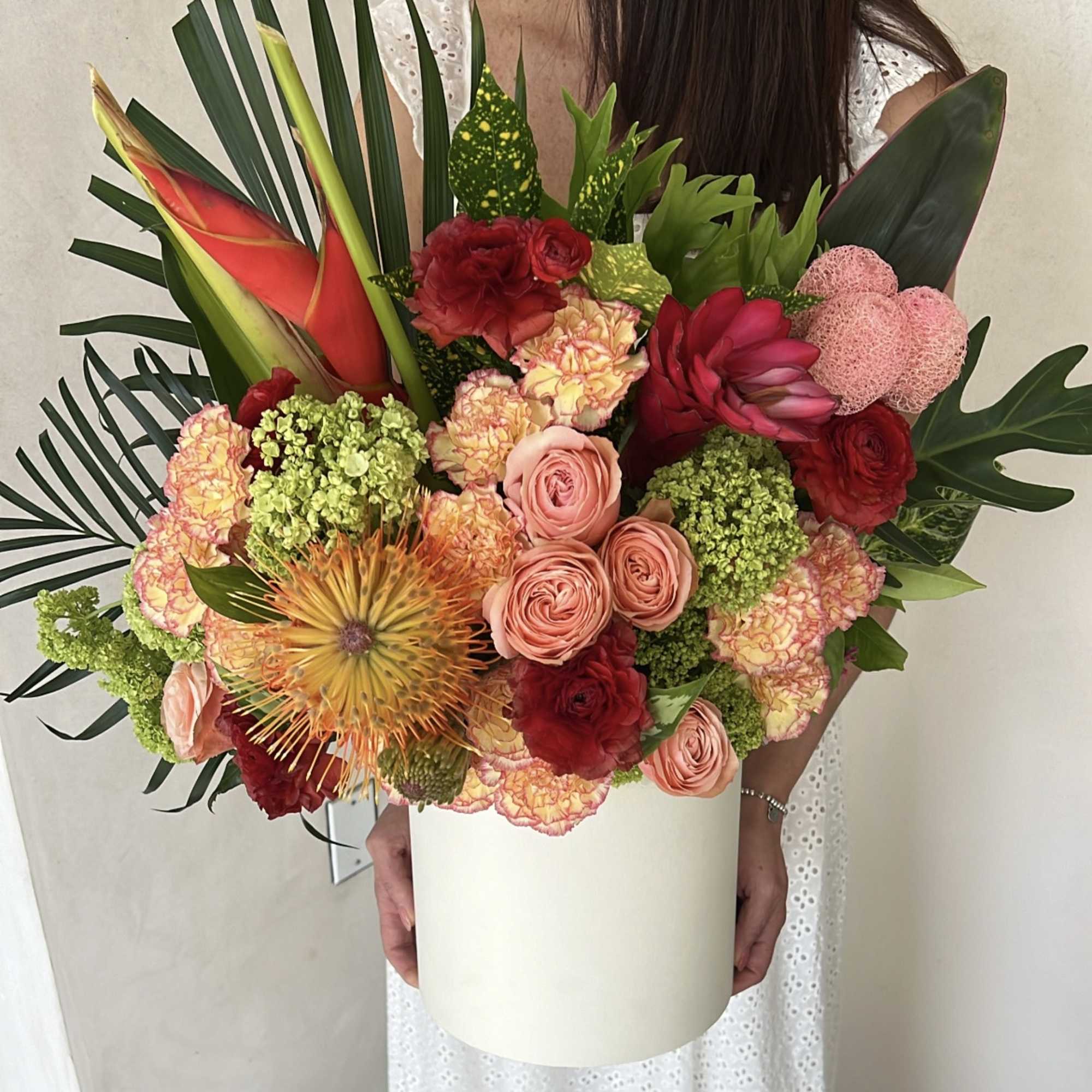 Large tropical bouquet with red and peach flowers in a white box