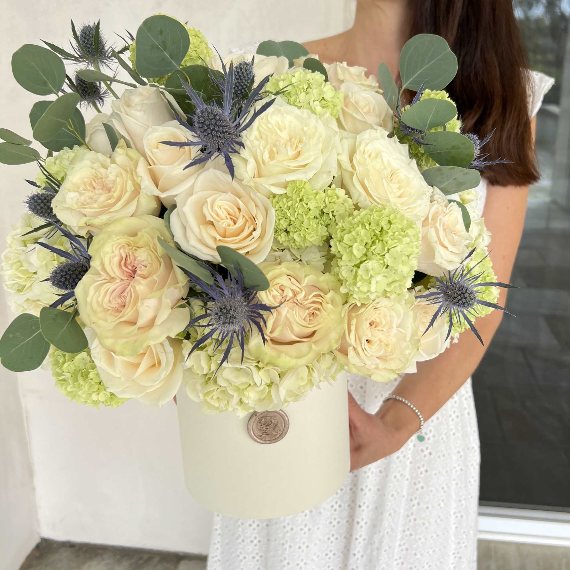 Bouquet of cream roses and green hydrangeas in a white hatbox