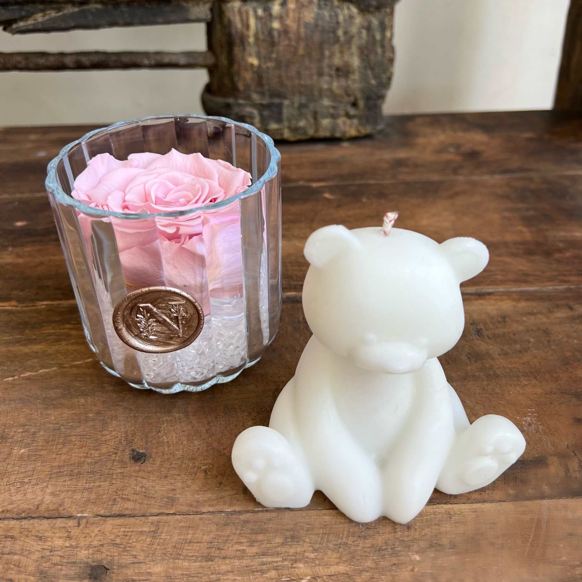 Pink rose in a clear glass holder beside a white bear-shaped candle