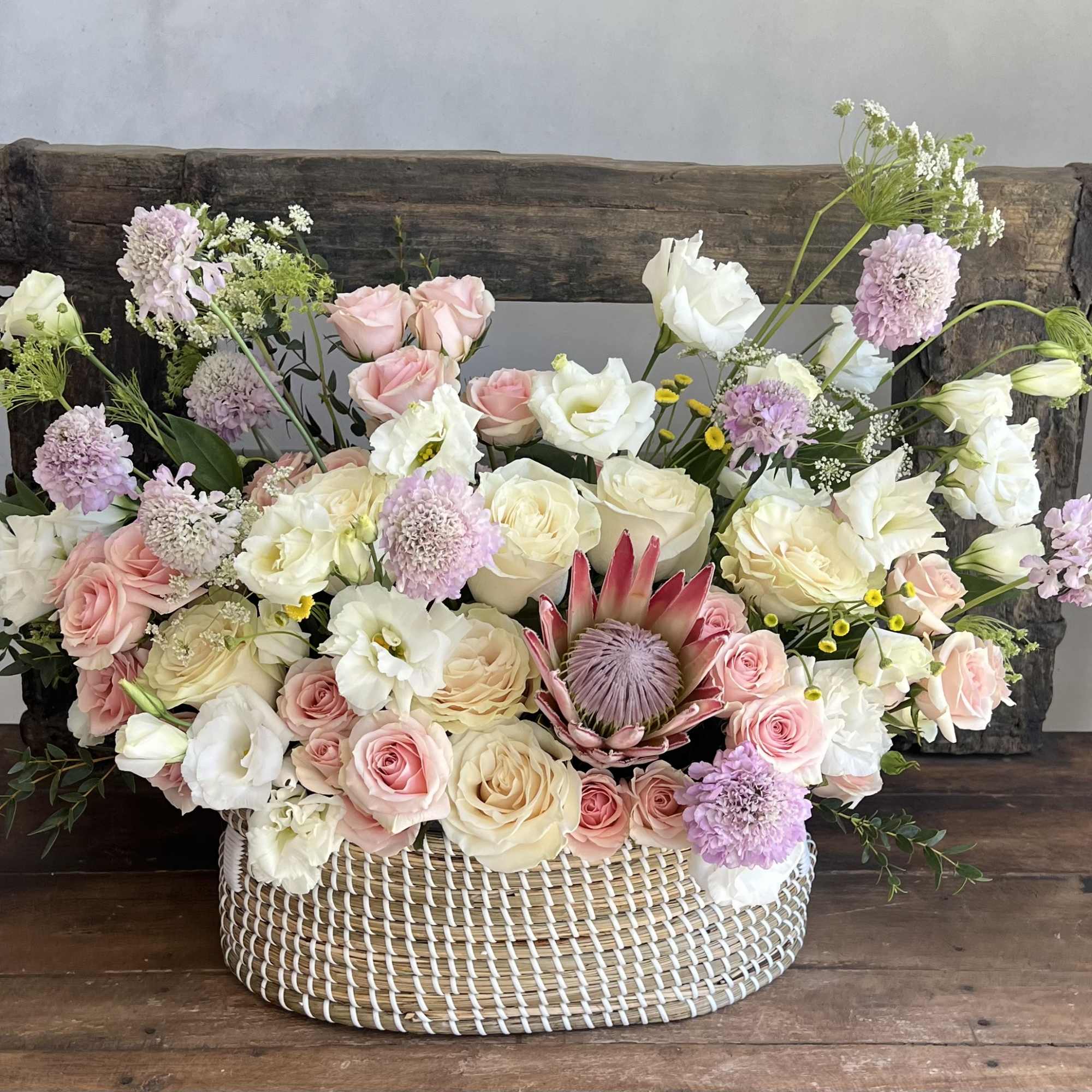 Pastel floral arrangement in a woven basket with roses and white blooms