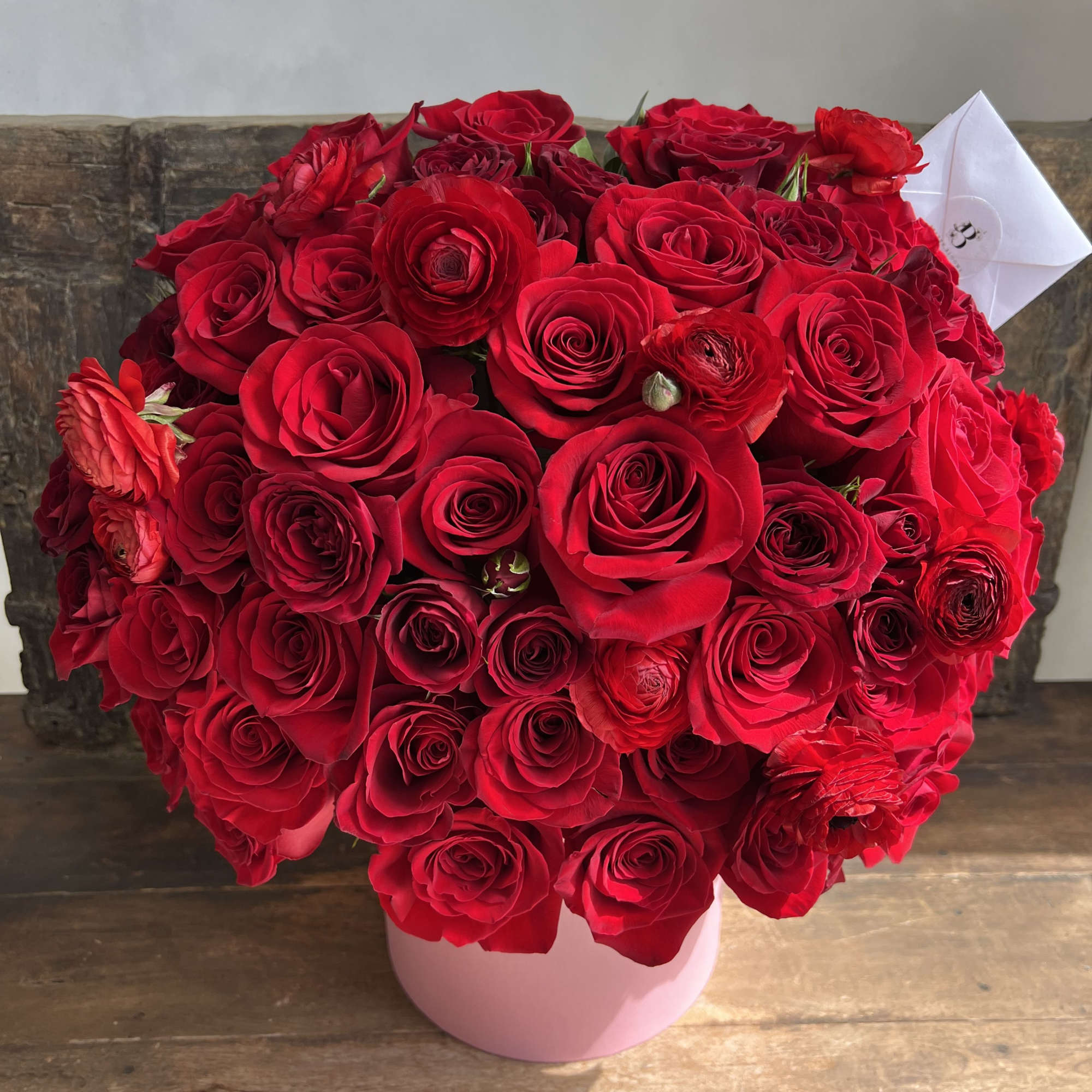 Large bouquet of red roses in a pink round box