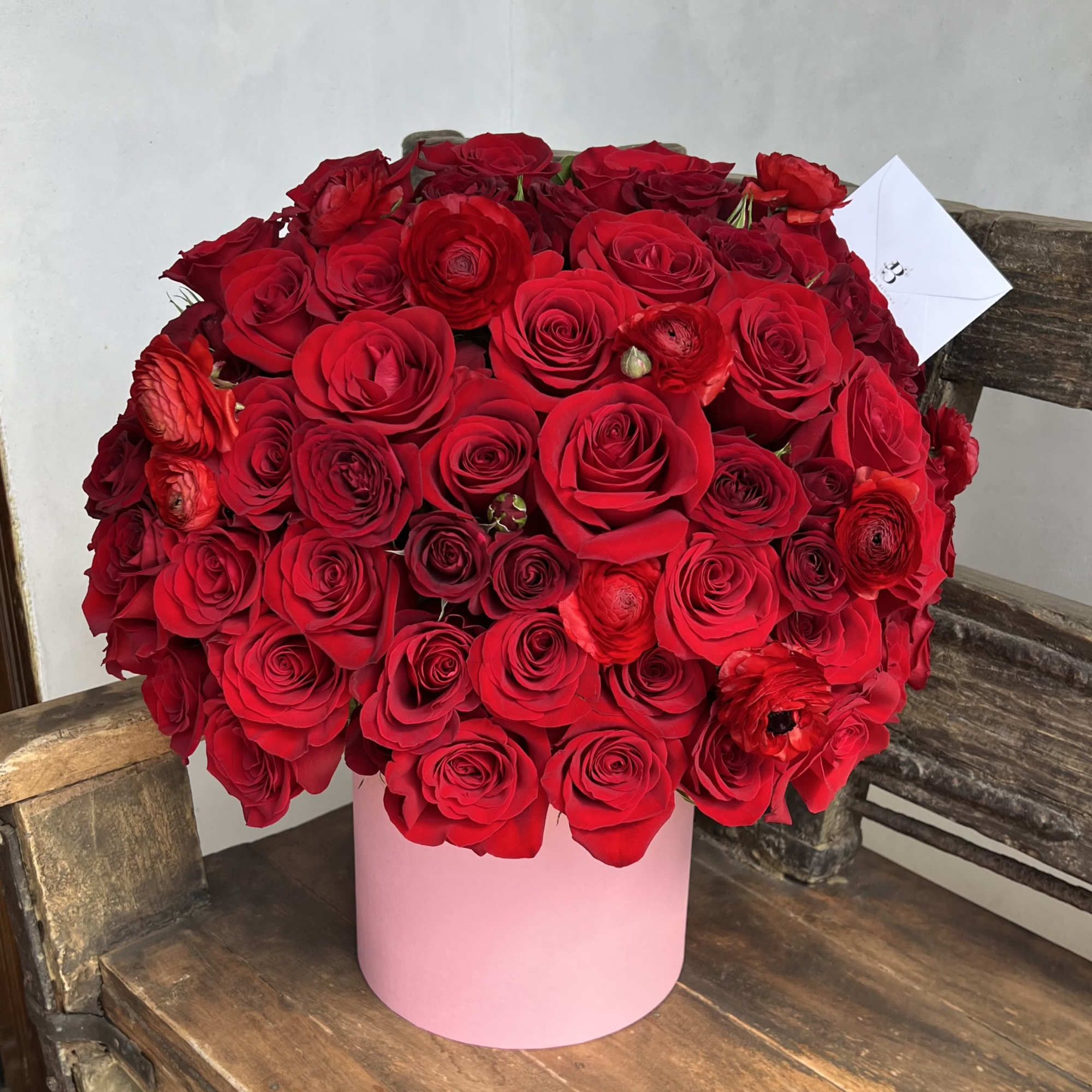 Large bouquet of red roses in a pink cylindrical box
