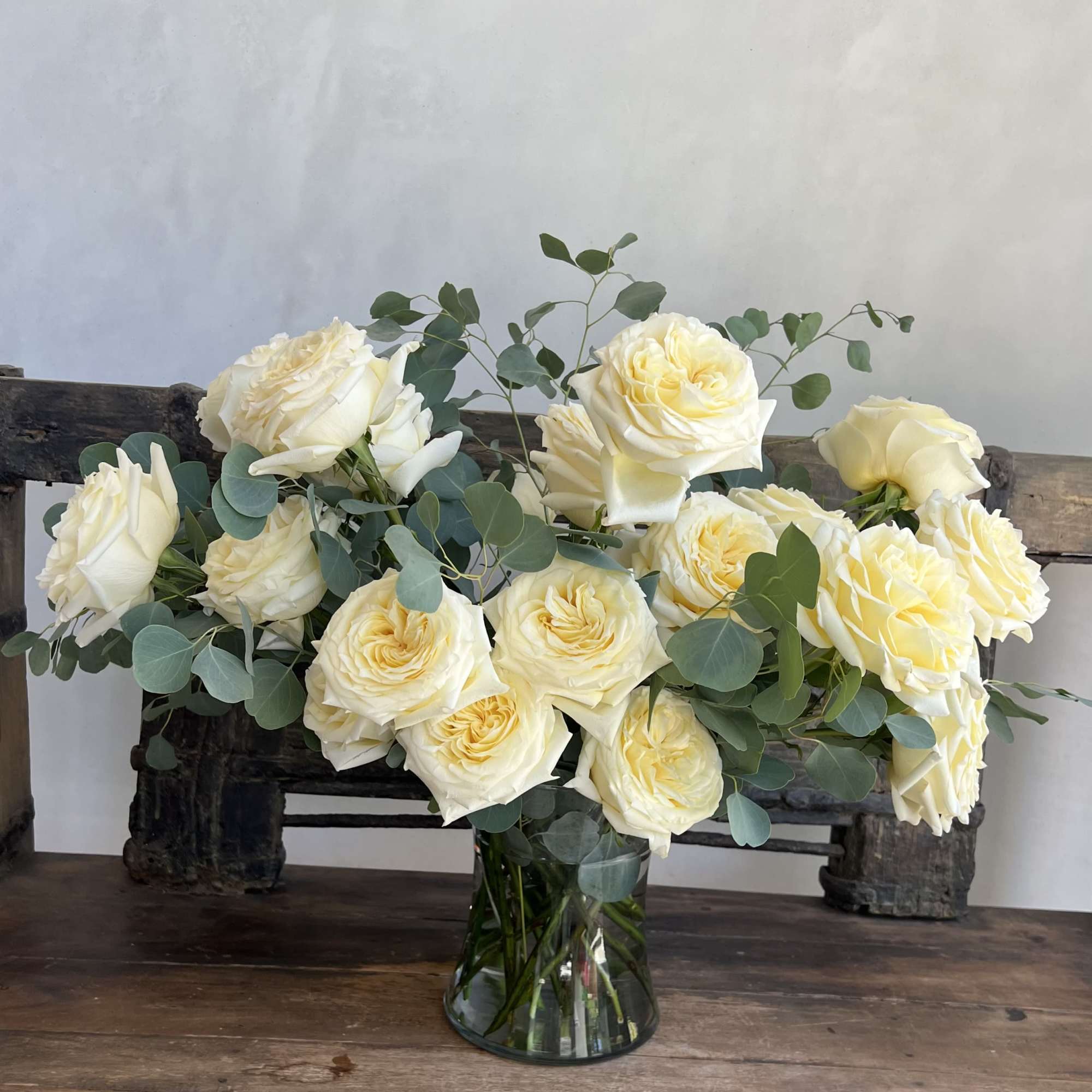 Cream roses arranged in a glass vase with eucalyptus