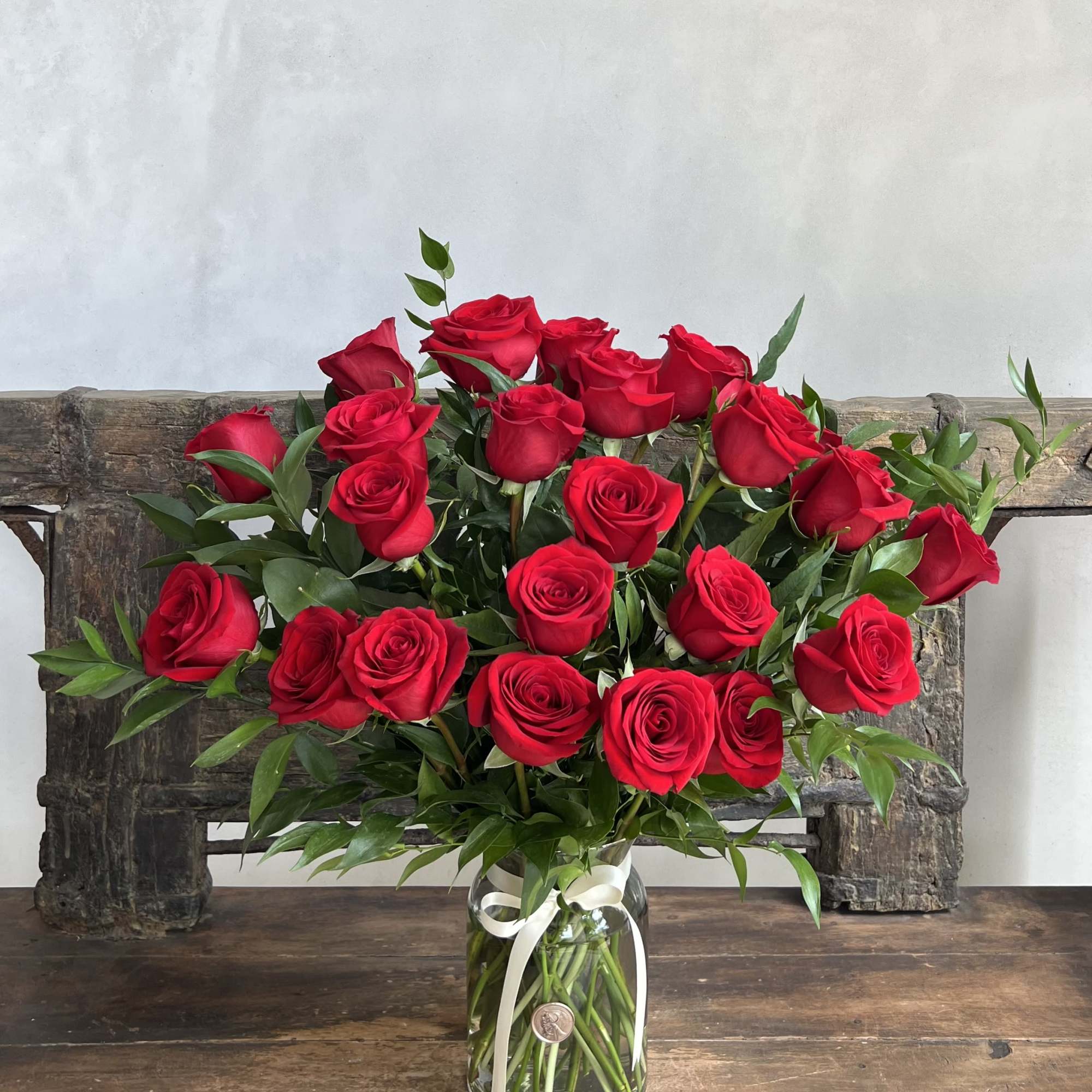 Bouquet of red roses in a clear glass vase with a white ribbon