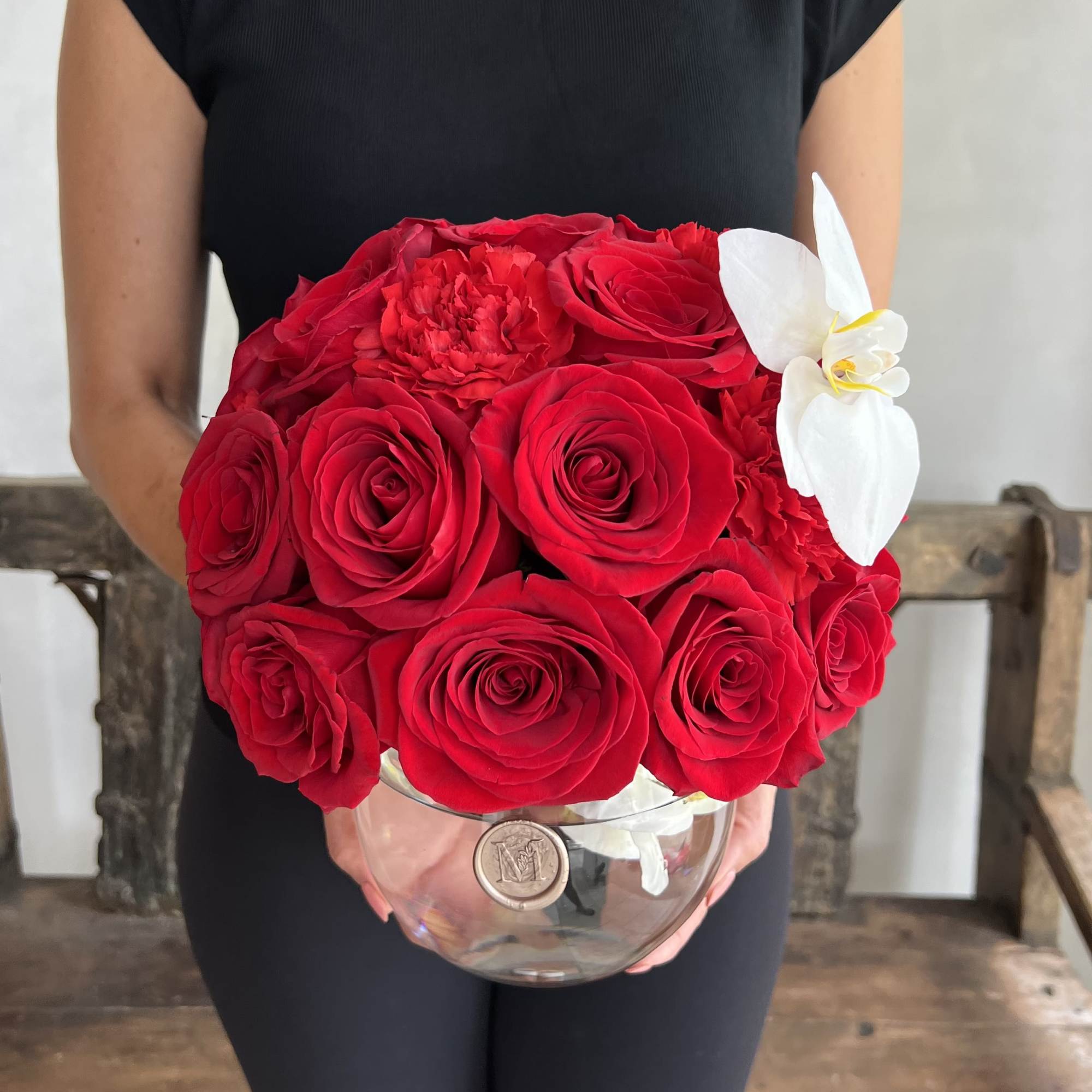 Red rose bouquet with a white orchid in a clear glass vase