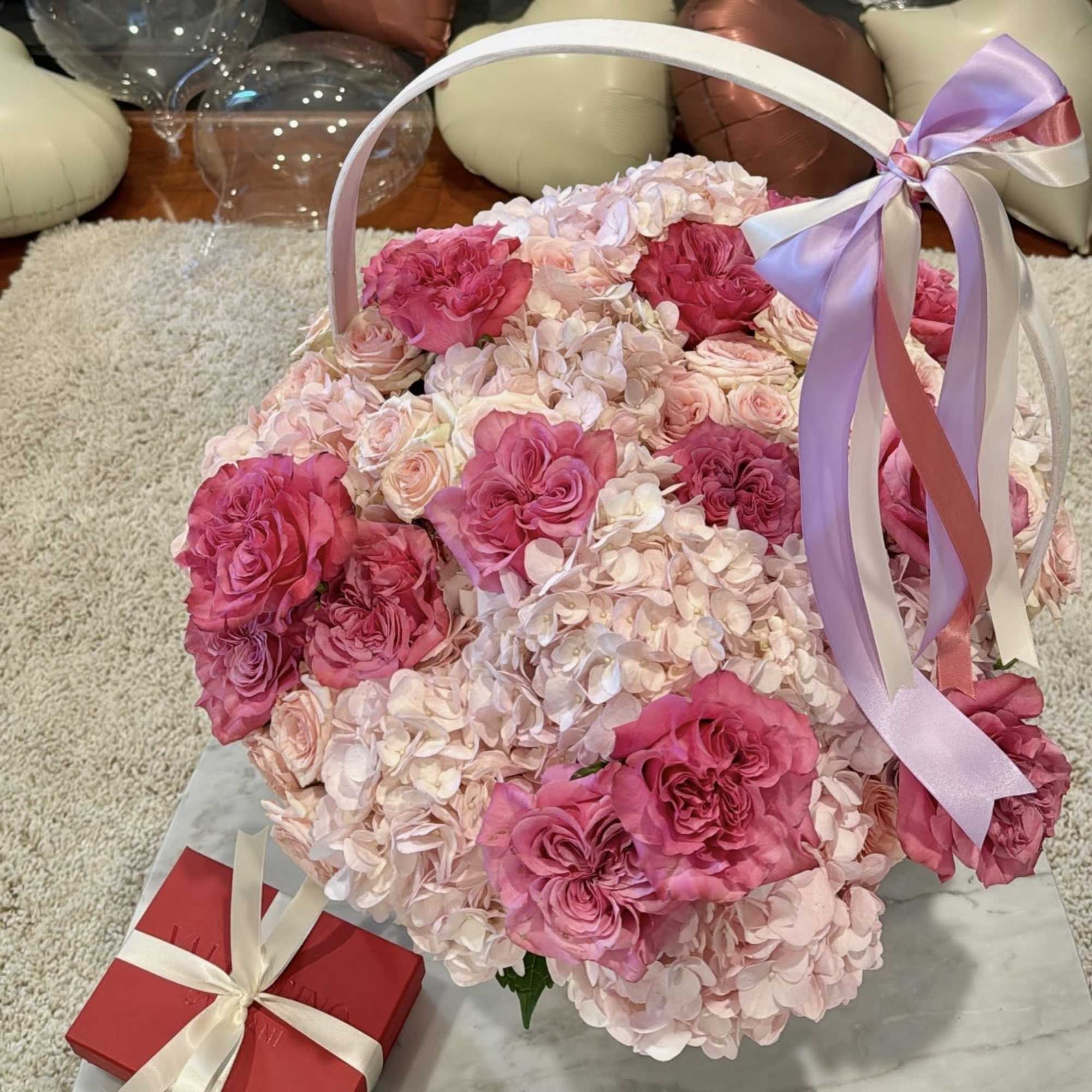 Basket of pink roses and pale hydrangeas with a ribbon bow