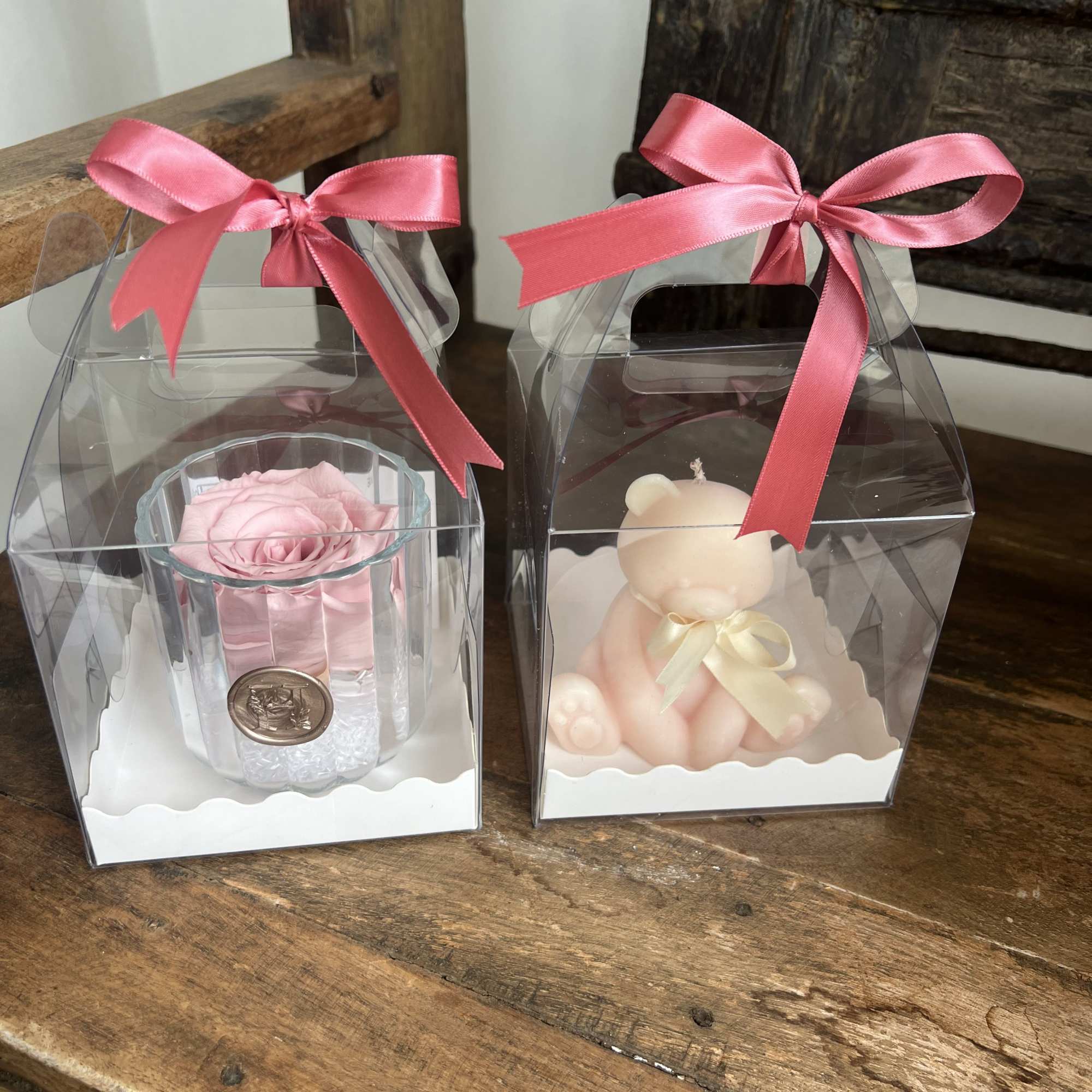 Two gift boxes with a pink rose and a teddy bear inside