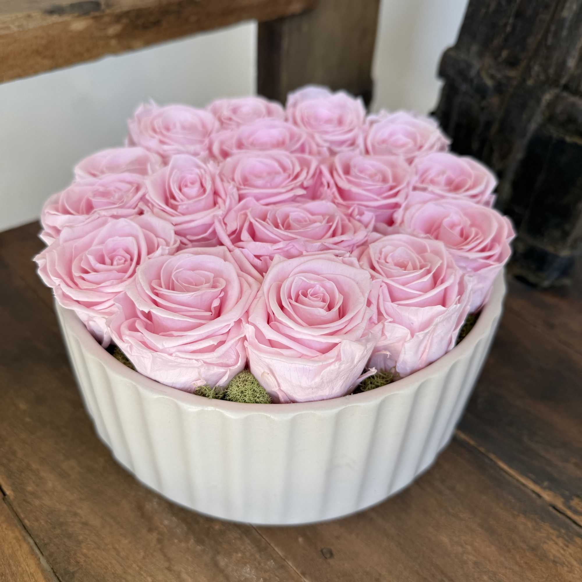 Pink roses arranged in a white round container