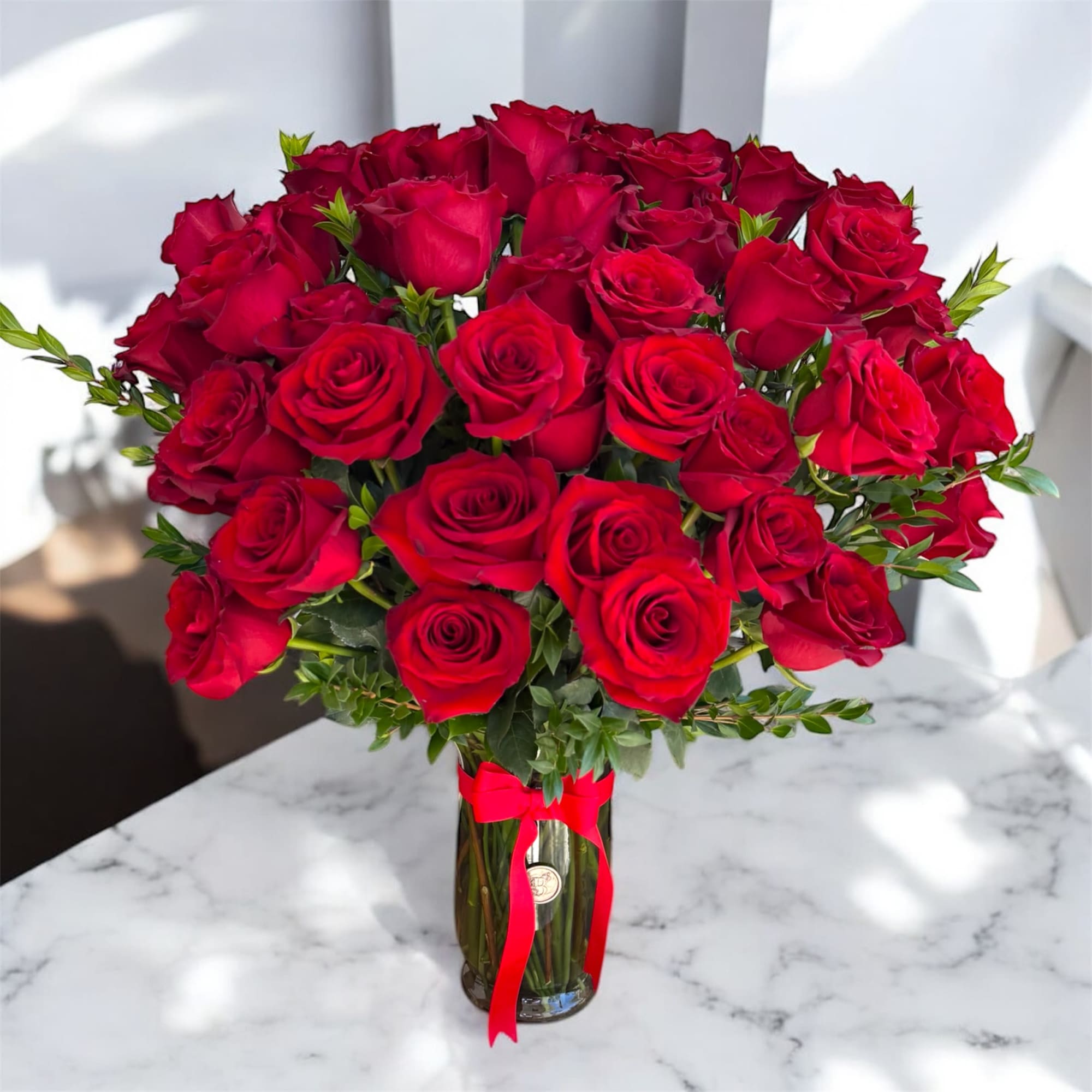 Bouquet of red roses in a glass vase with a red ribbon