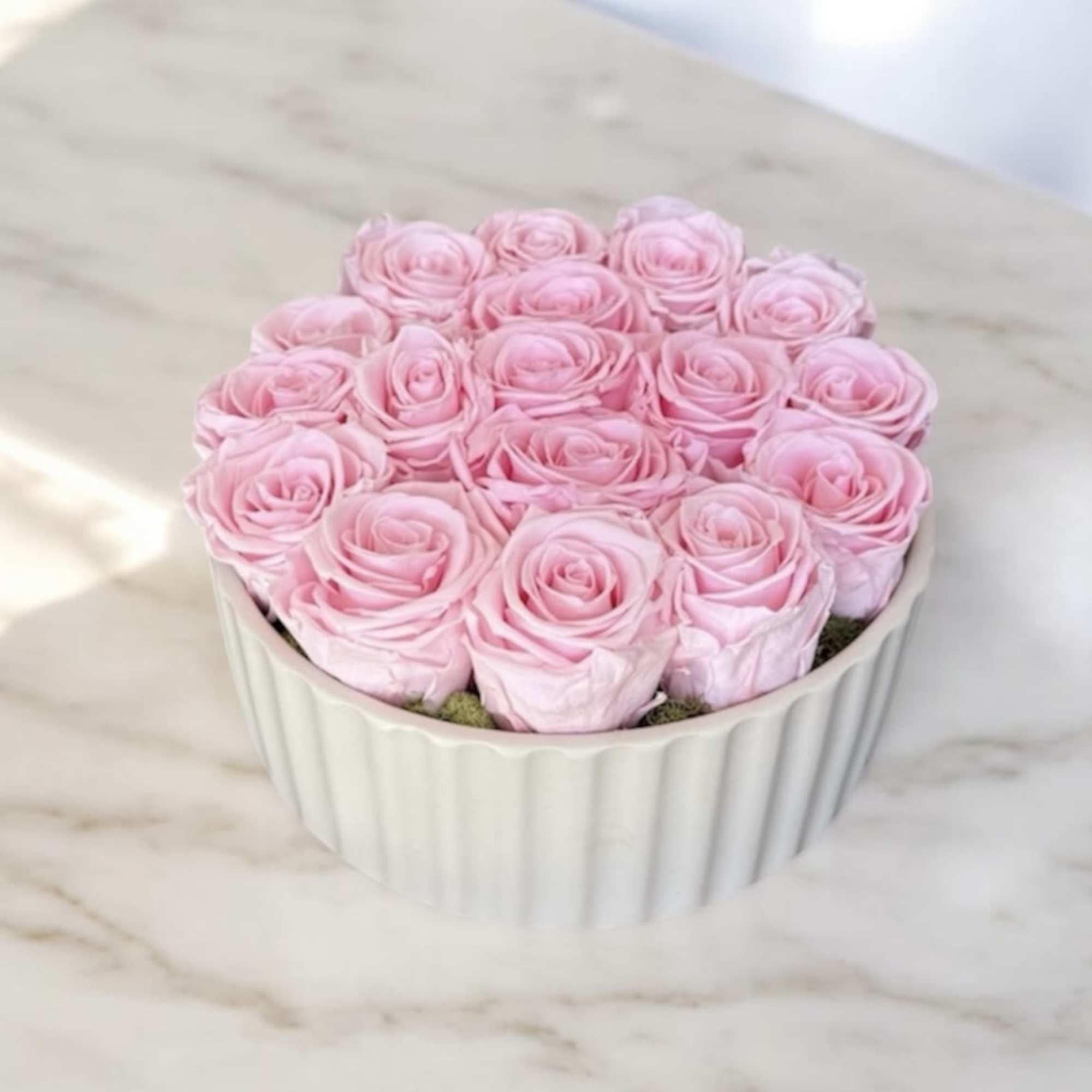 Pink roses arranged in a white fluted container