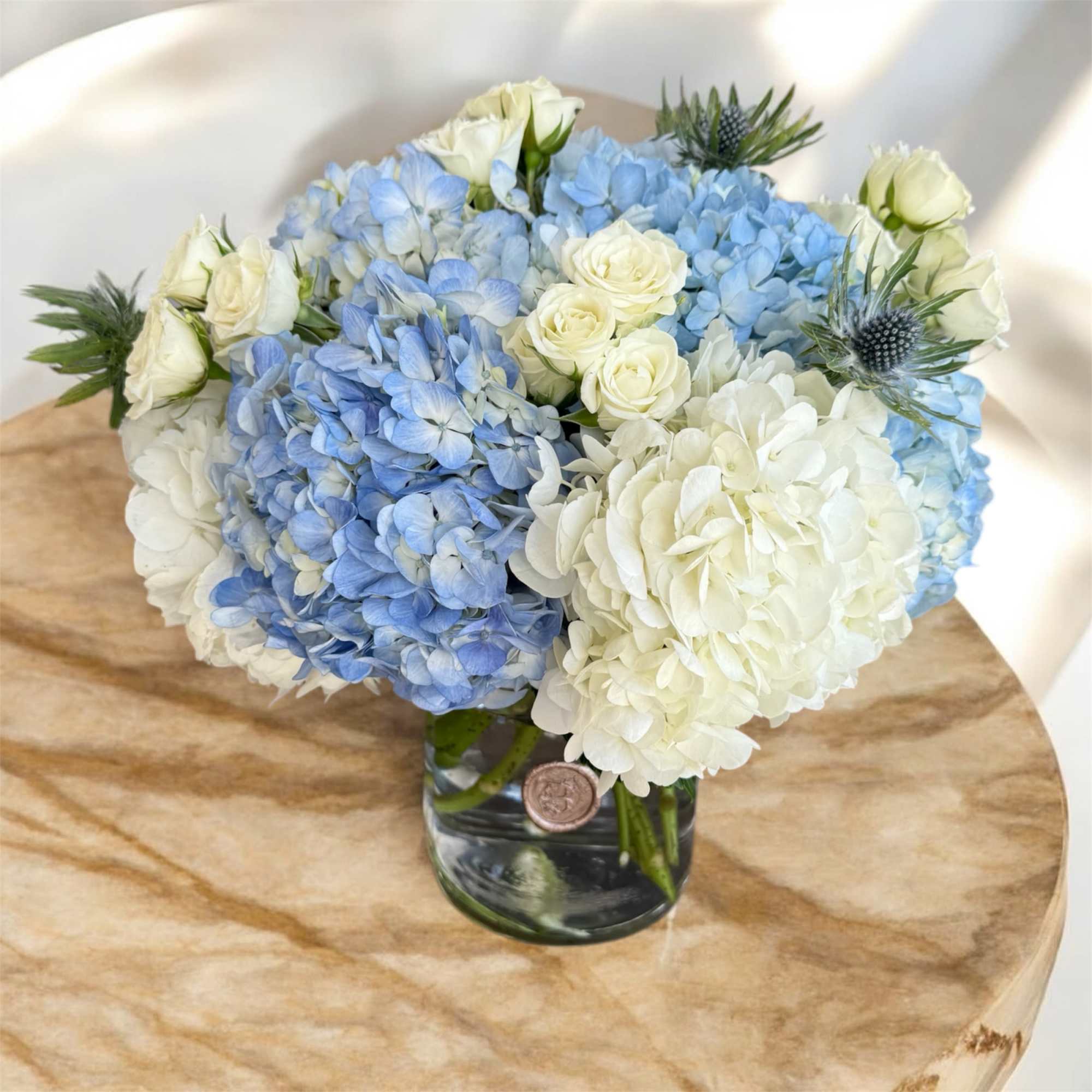 Blue and white hydrangea bouquet with white roses in a glass vase