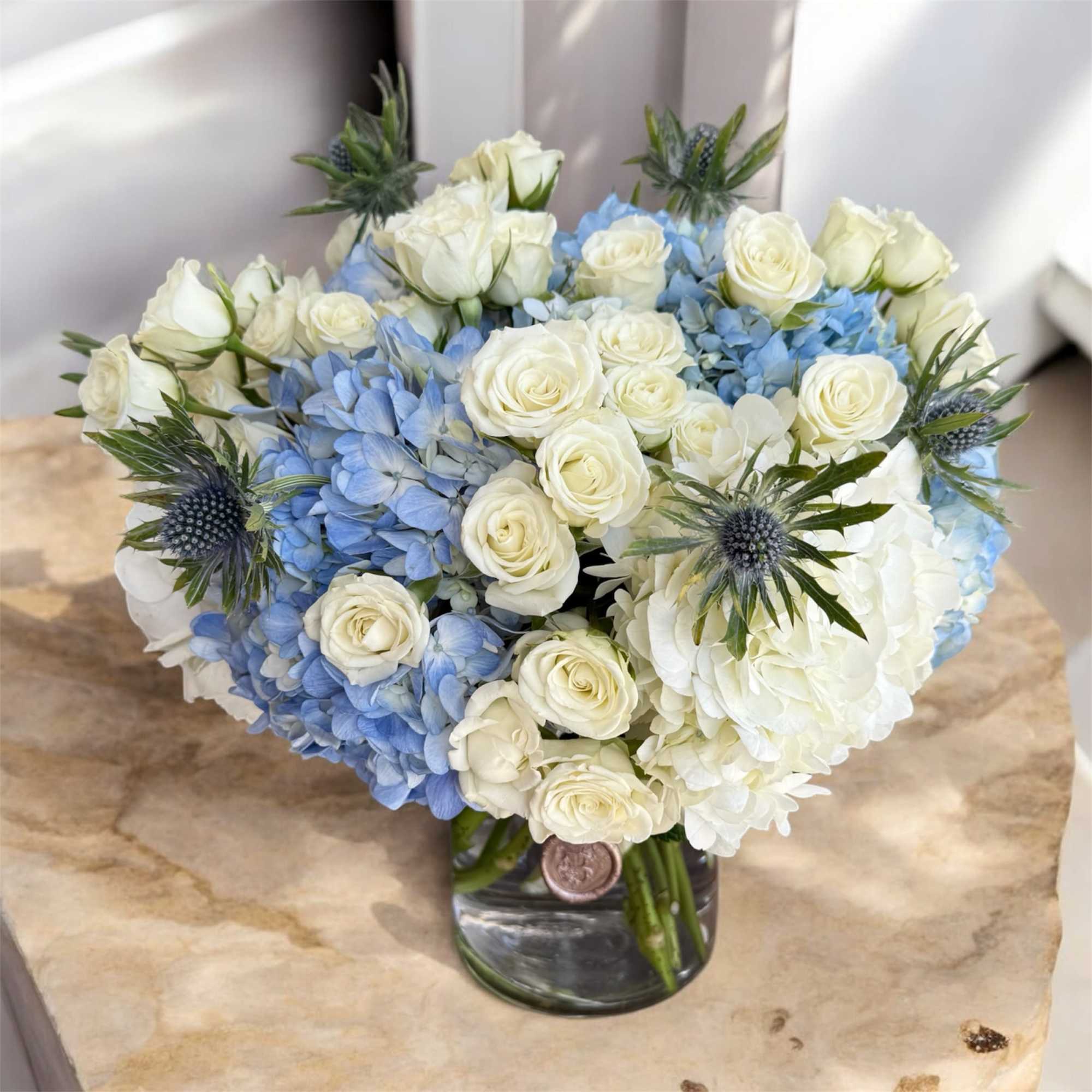 White roses and blue hydrangeas in a glass vase