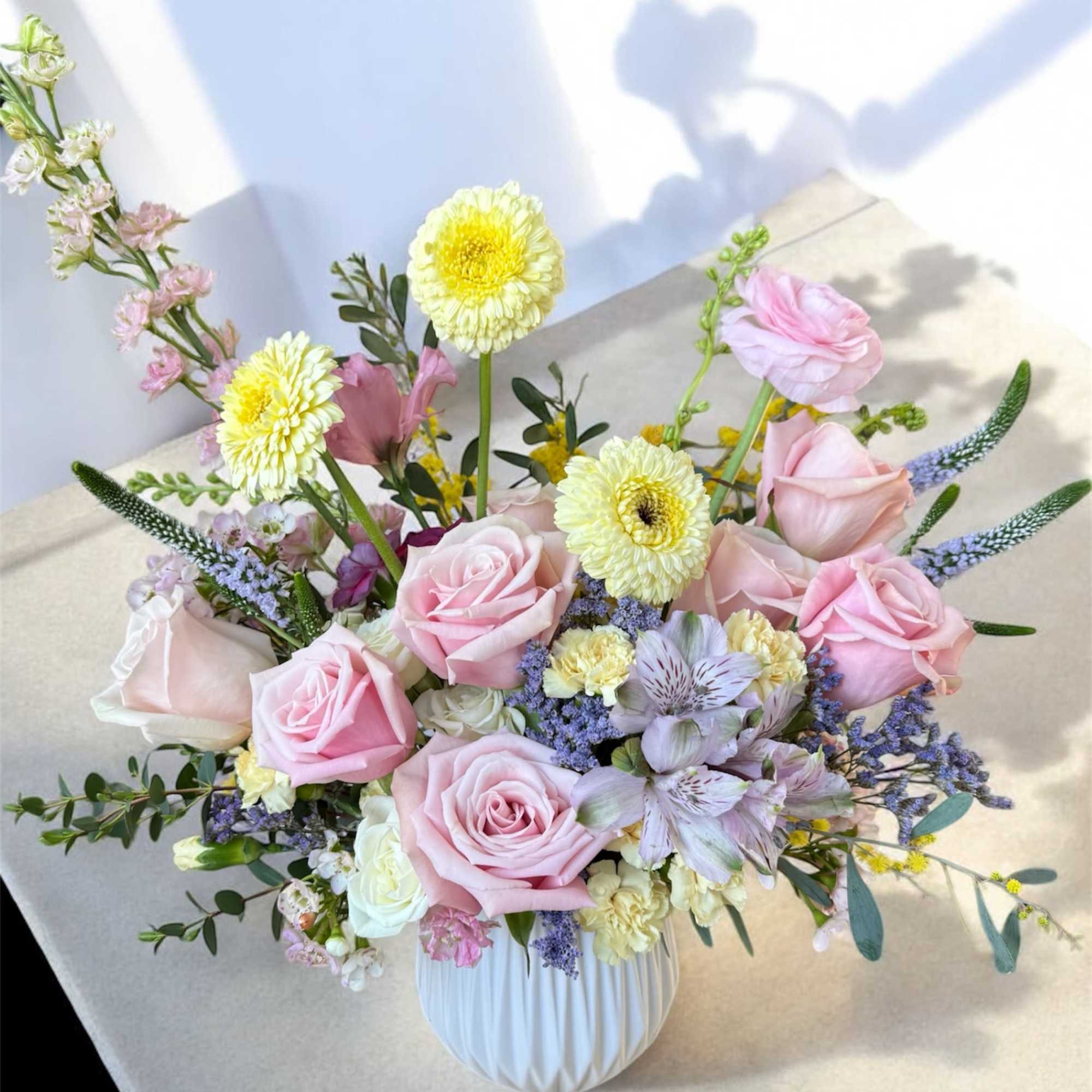 Pink roses and pastel mixed flowers arranged in a white vase