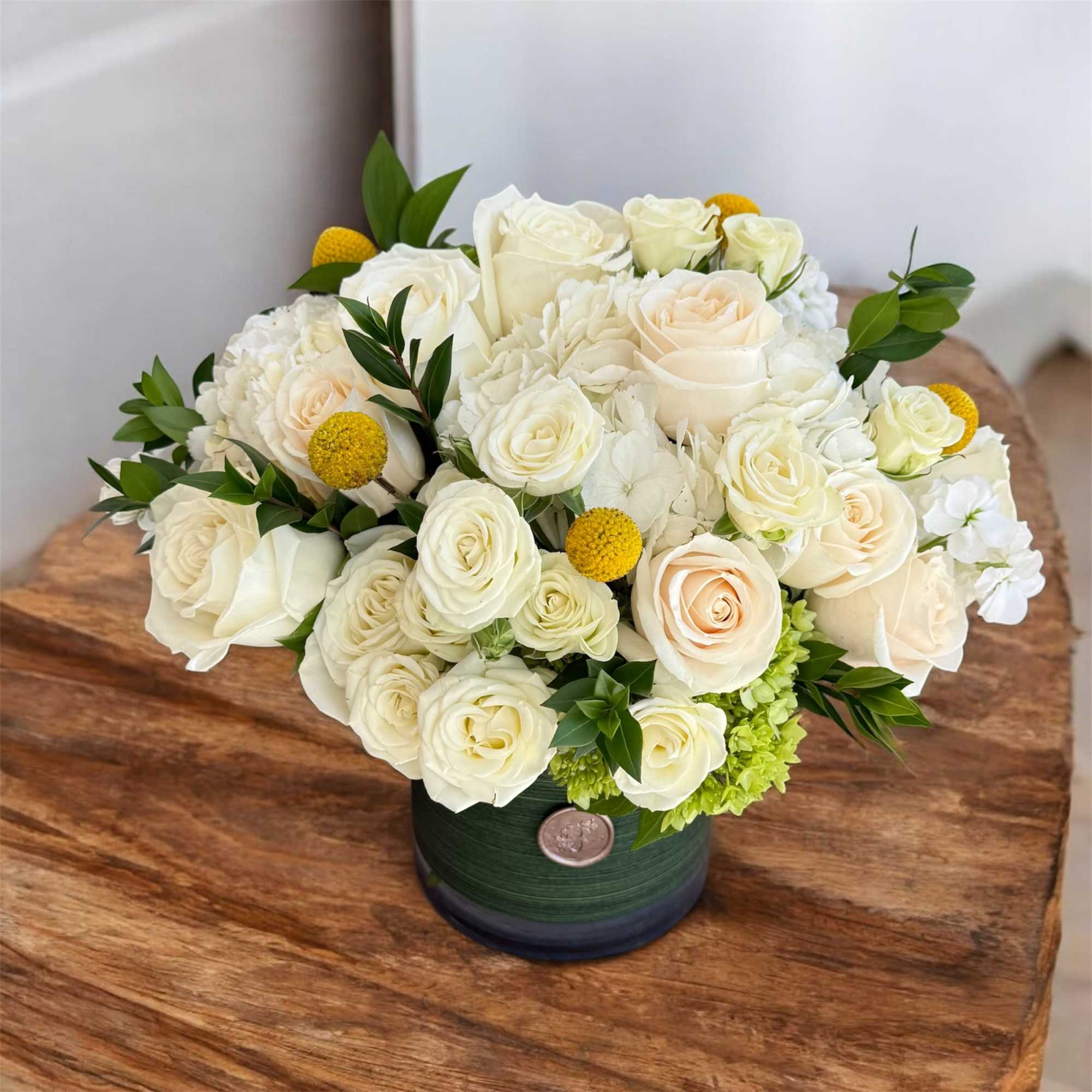 White rose bouquet in a green vase with yellow accents