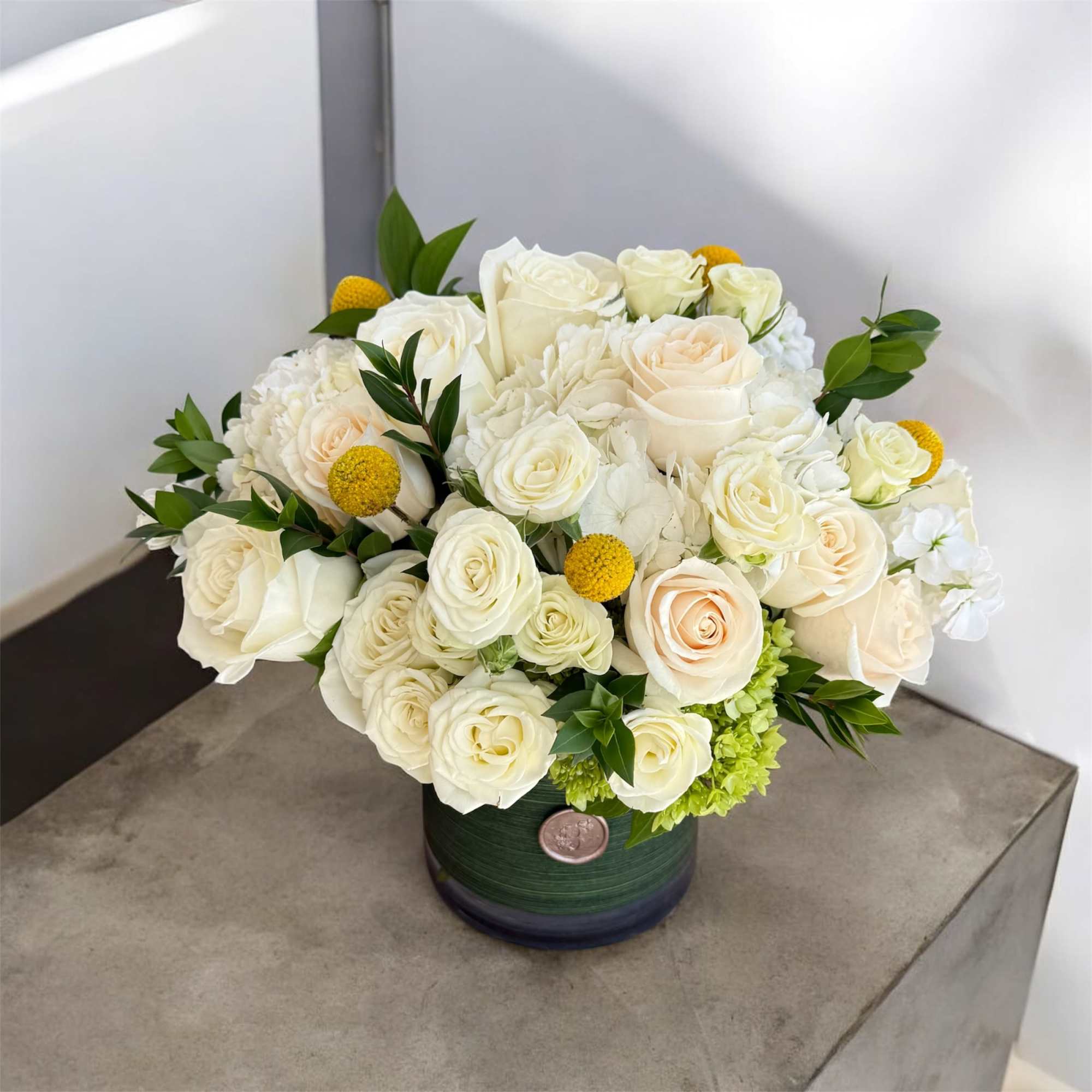 Cream roses and white blooms arranged in a green vase