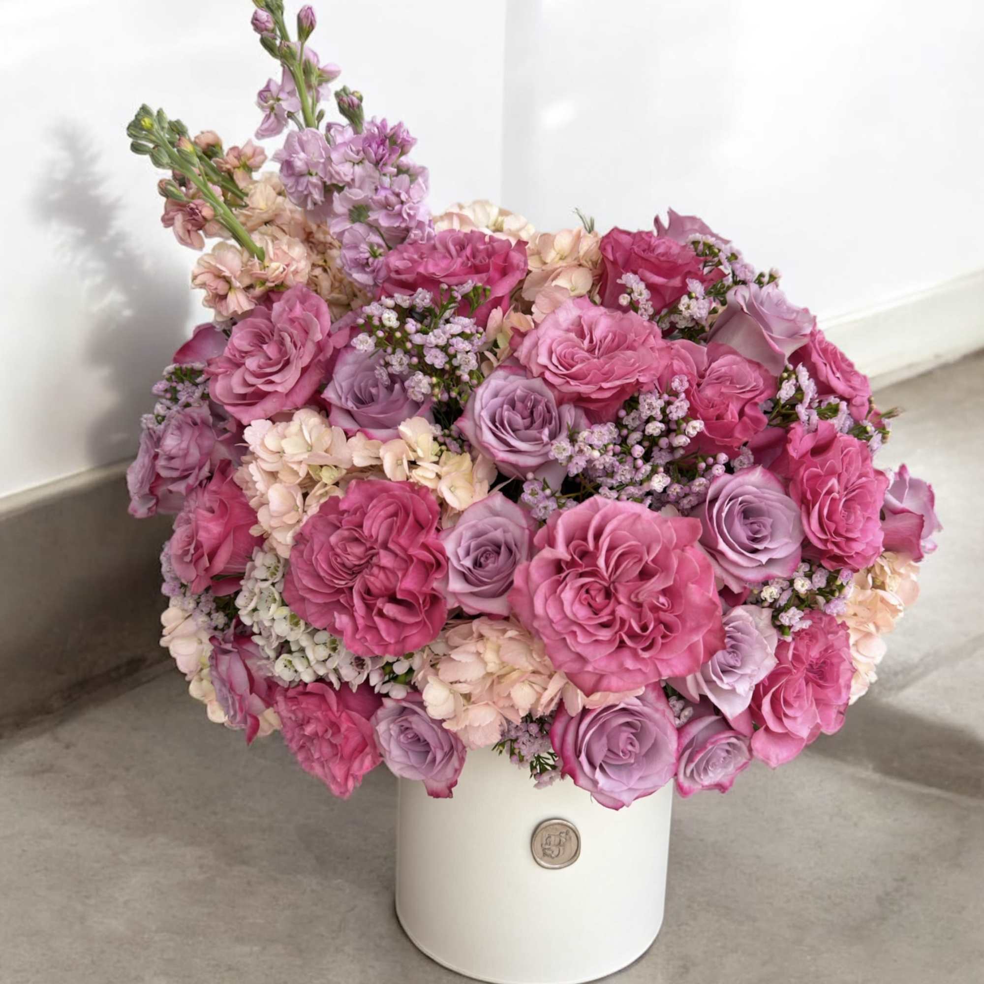 Pink and lavender rose bouquet in a white hatbox