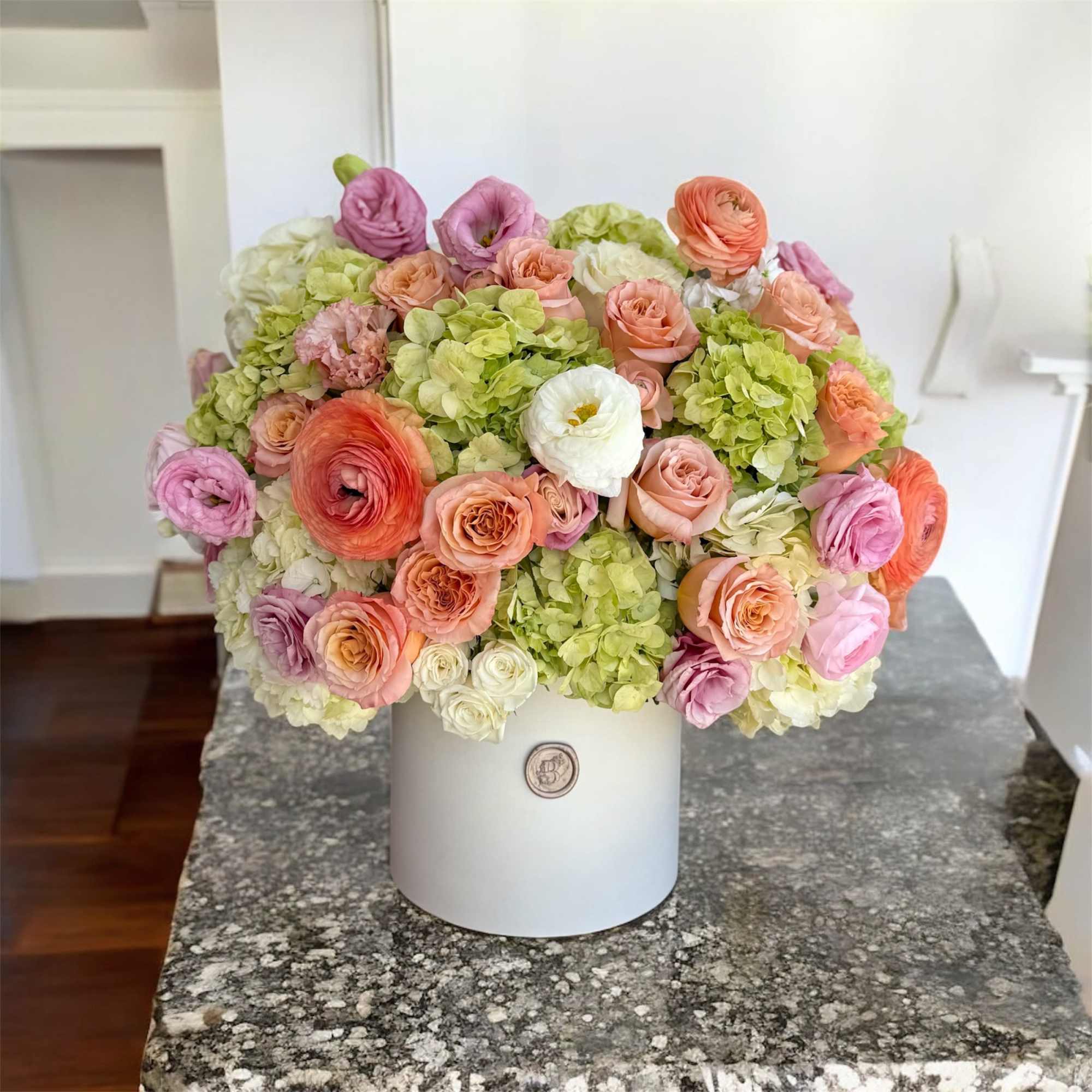 Bouquet of peach, pink, and green flowers in a white hat box